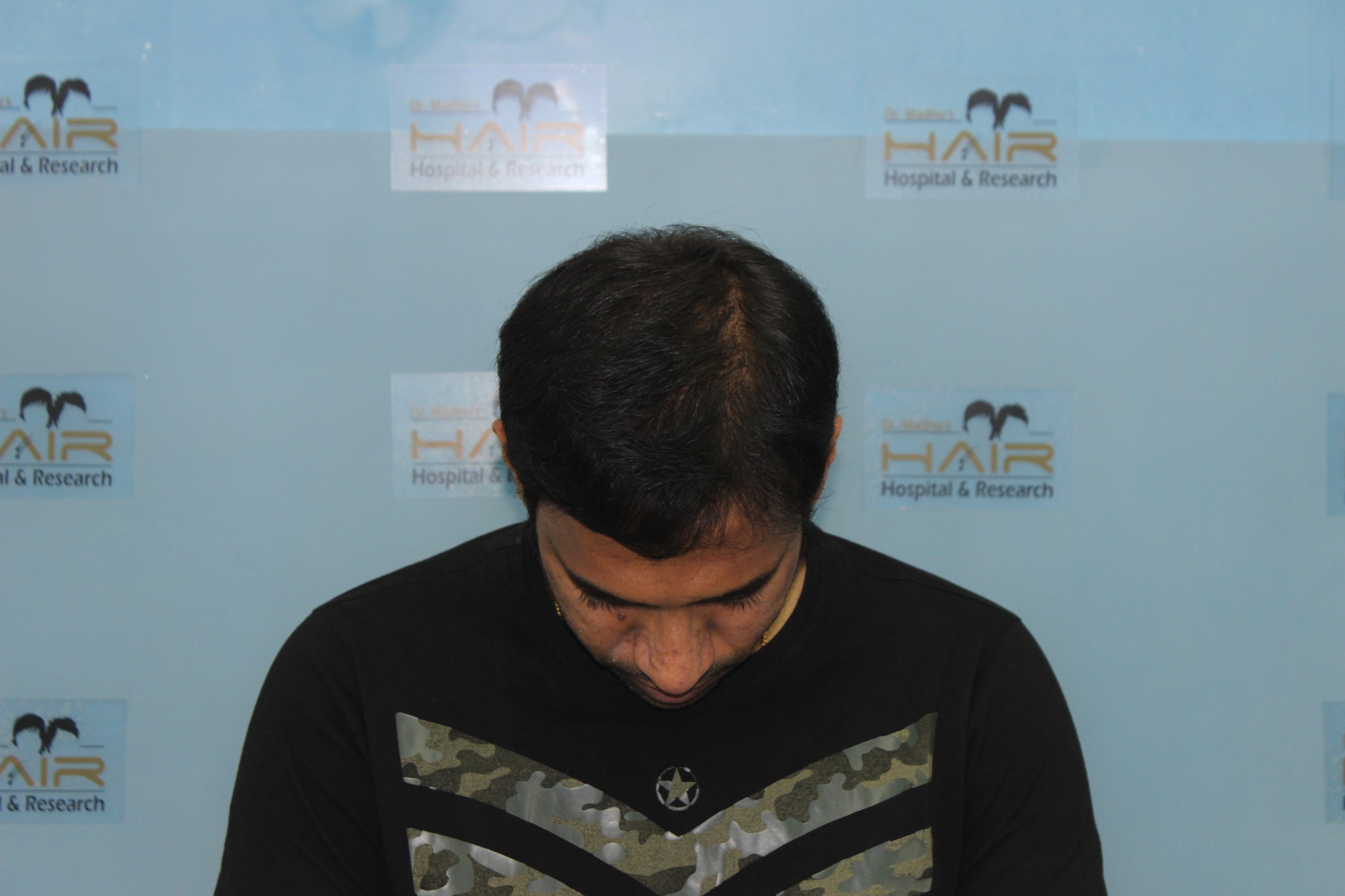 Person with long dark hair holding bouquet of white flowers near face against softly lit background