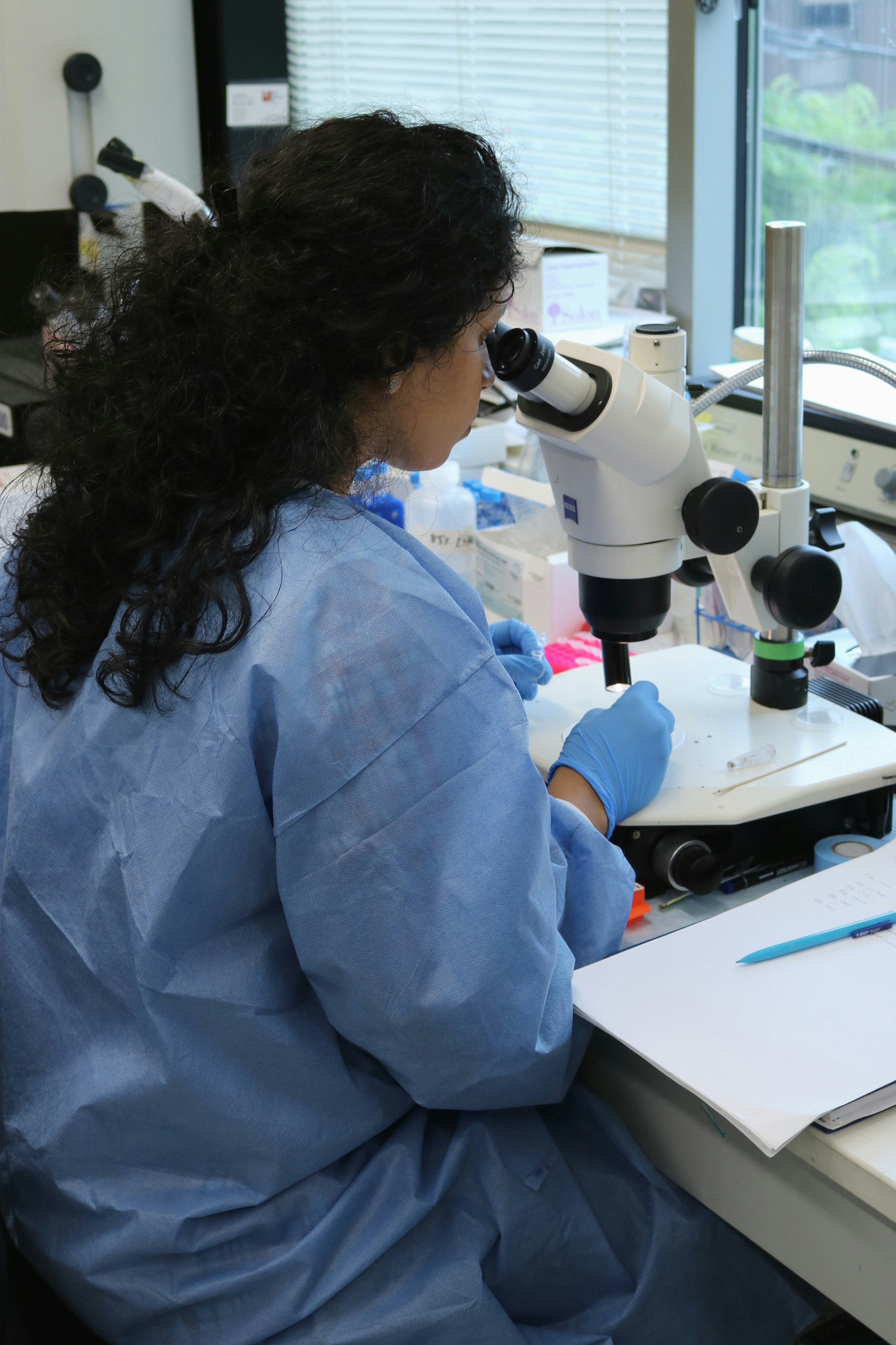 a woman in a lab coat looking through a microscope
