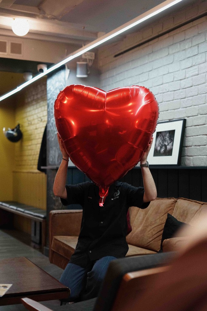 Personne tenant un ballon cœur rouge dans l'atmosphère chaleureuse d'un salon ECLA Group