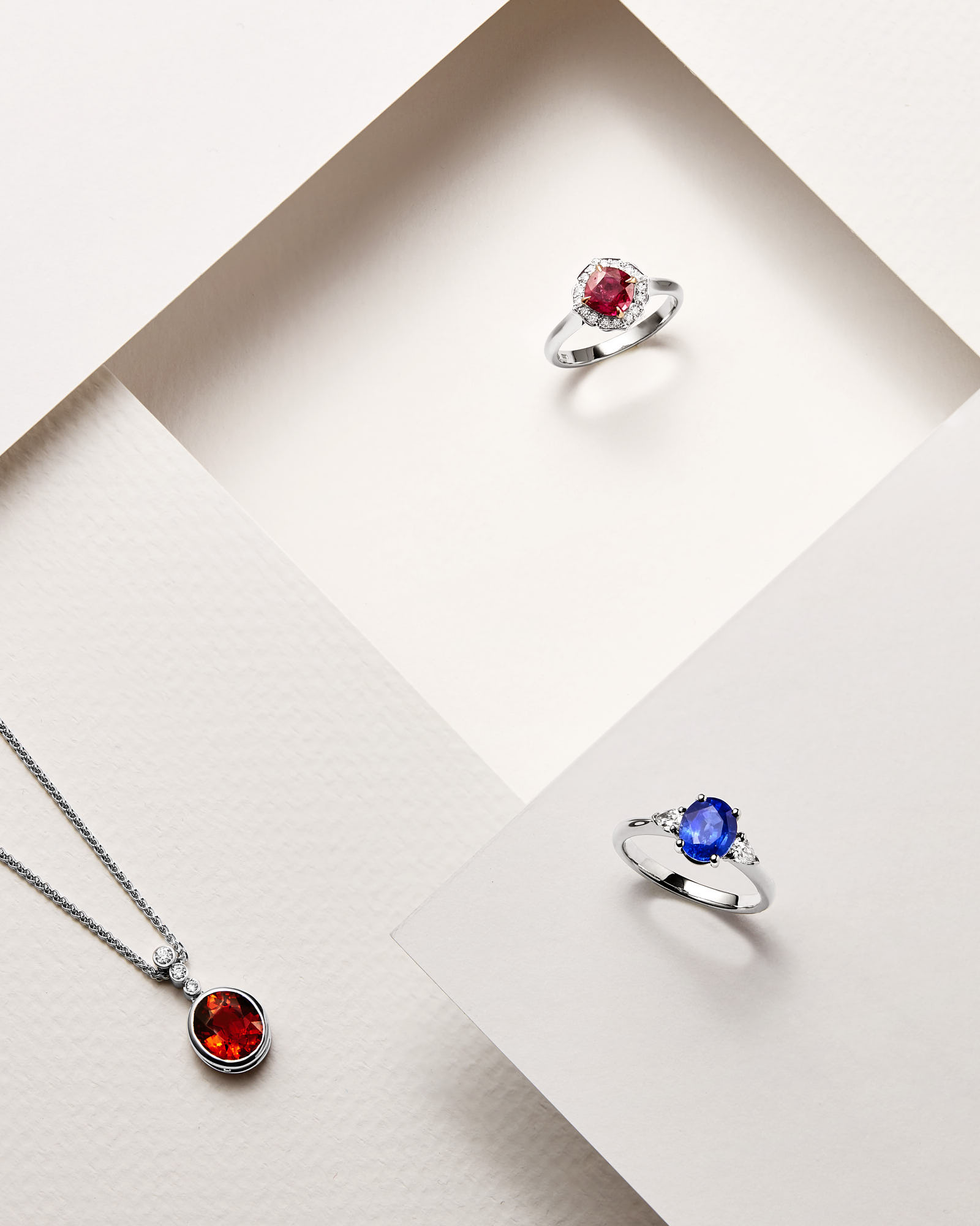 Elegant gemstone jewelry collection with ruby and sapphire rings and a garnet pendant necklace.