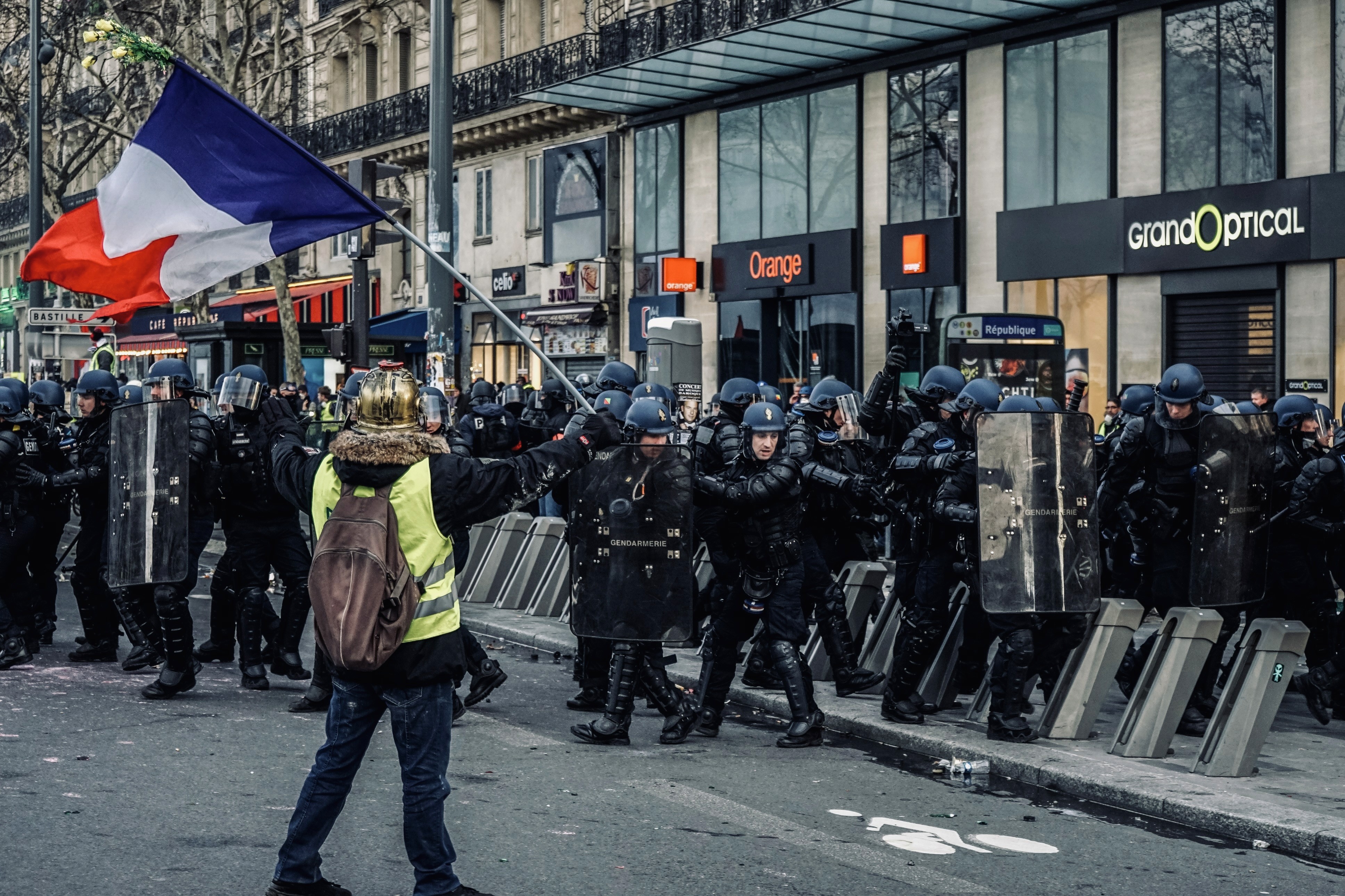 Manifestant portant un drapeau français face à une ligne de gendarmes à Paris