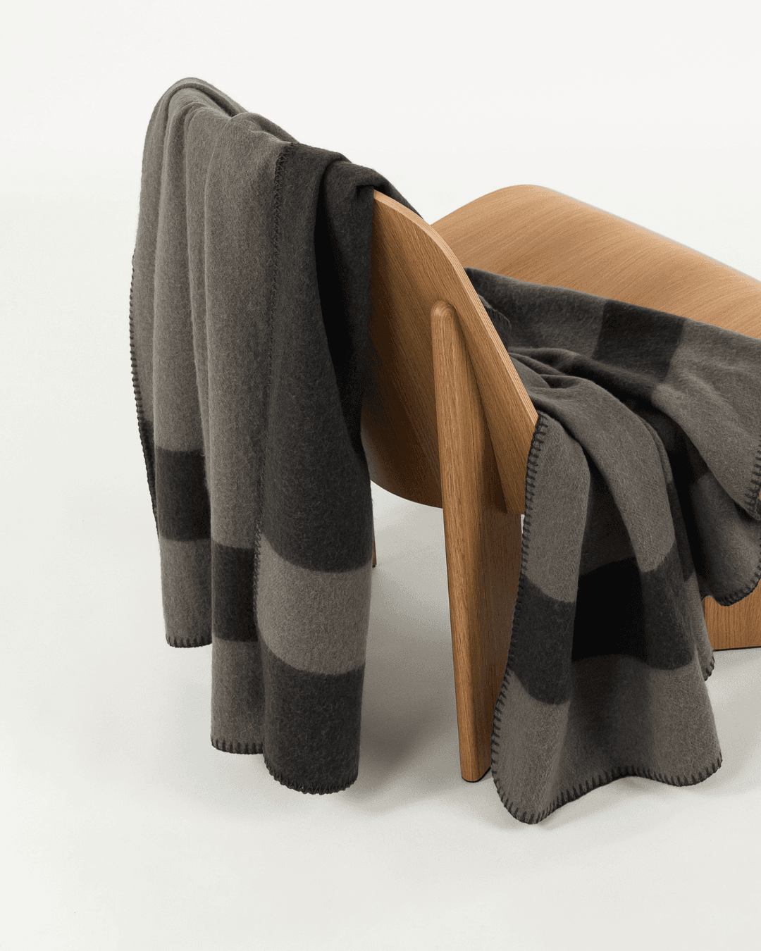 Merino wool blanket in peak/caviar draped over a wooden chair