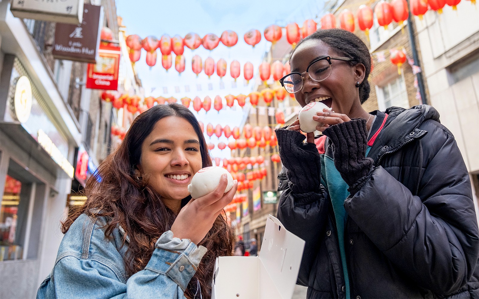 ロンドンのソーホーでランタンの下、食べ歩きツアーを楽しむ観光客がバオバンを味わっています。