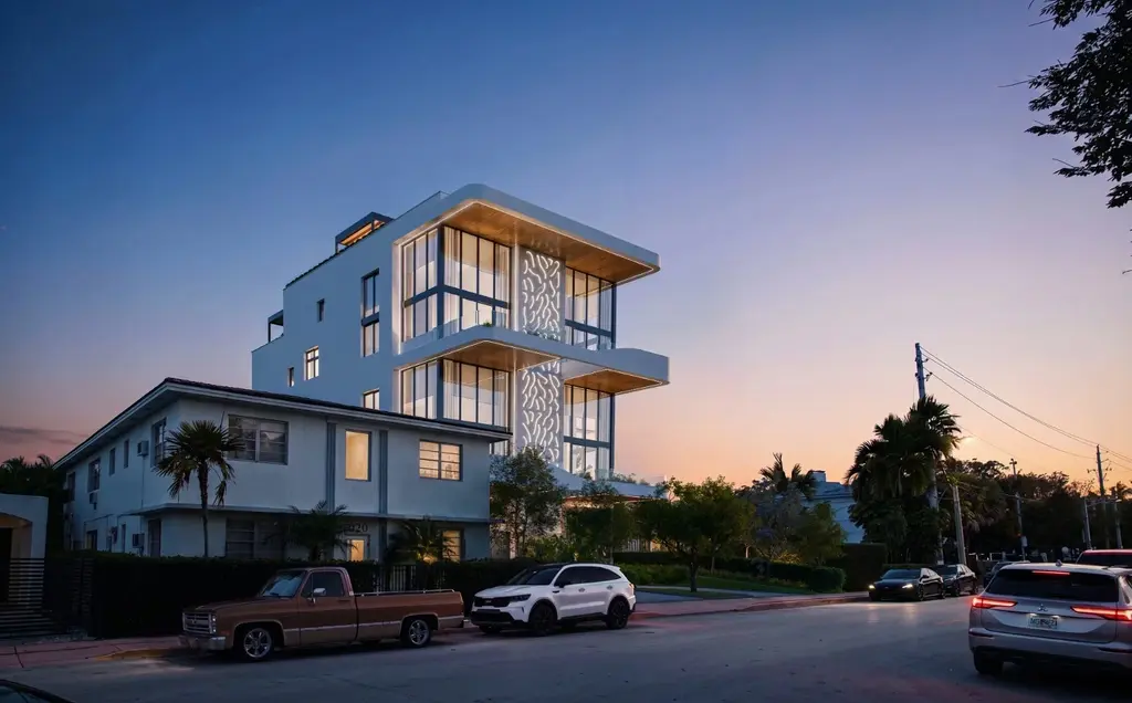 Byron Avenue Residence in South Beach, Miami Beach, rising behind a neighboring low rise building at sunset, with glass corners and a lit screen facade