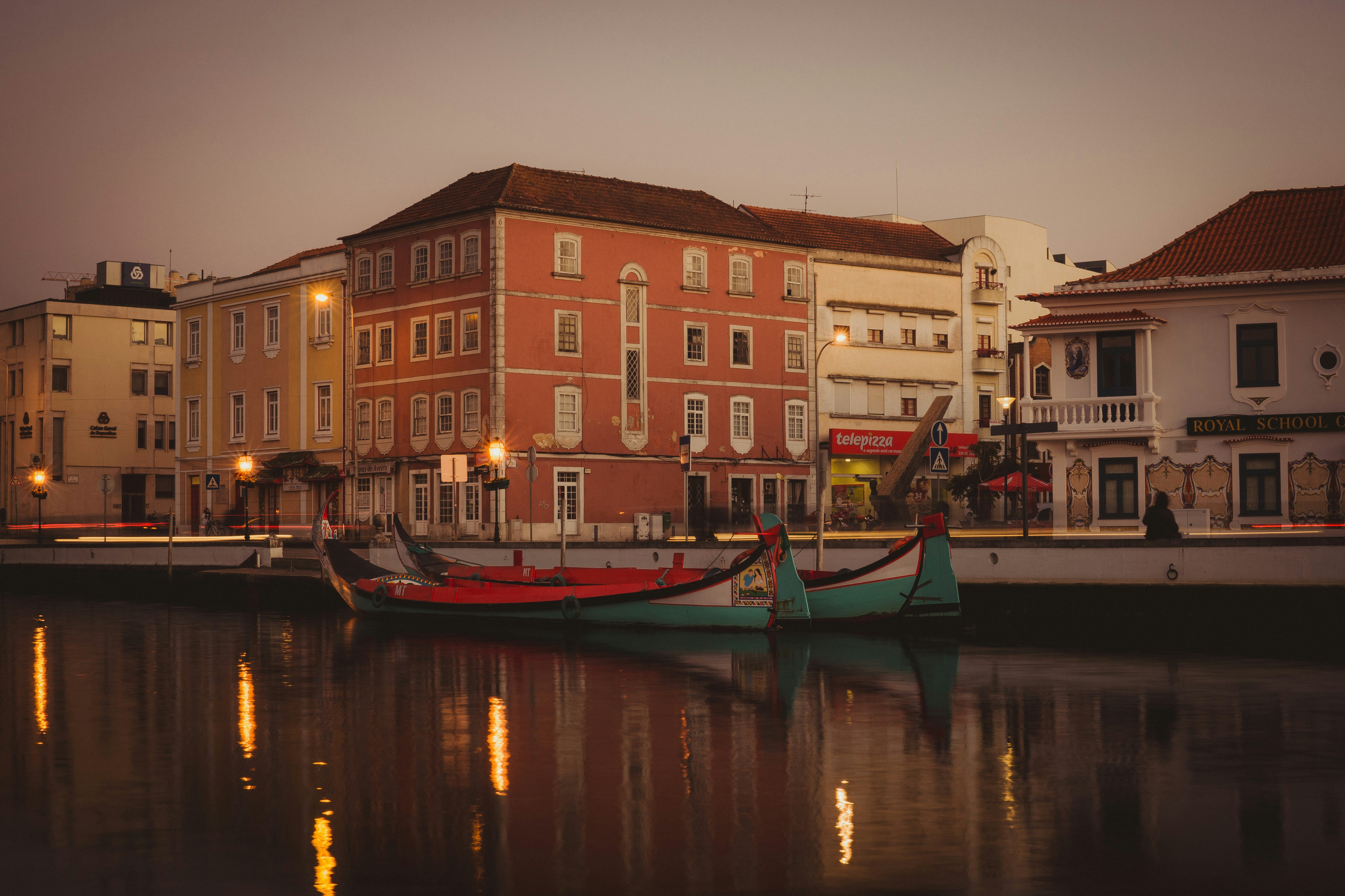 teal and red boat on river under gray sky