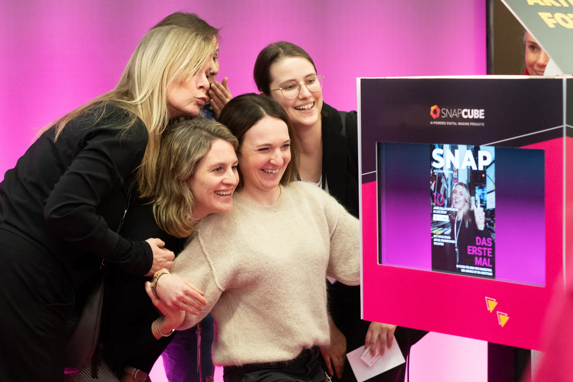 Besuchergruppe nutzt ein SnapCube® Fotomodul und betrachtet das aufgenommene Gruppenfoto auf dem Bildschirm.