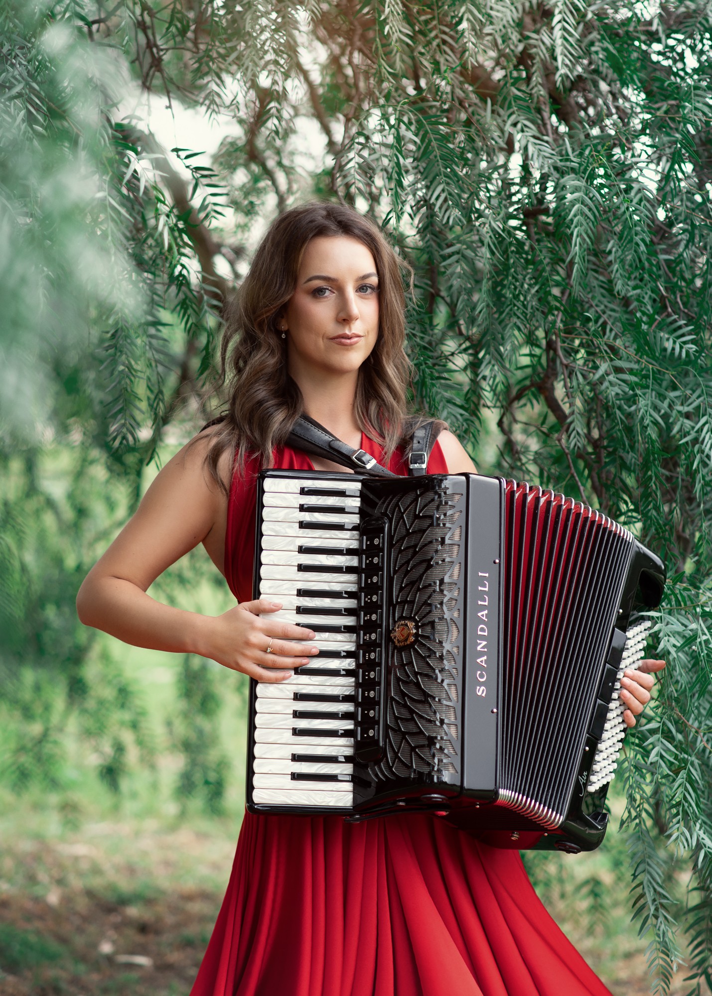 Lucy wearing professional black clothing and playing her accordion.