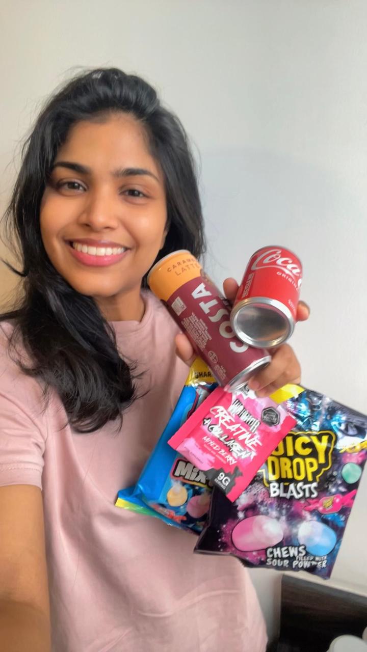 Student holding Costa, Coca-Cola and snack samples