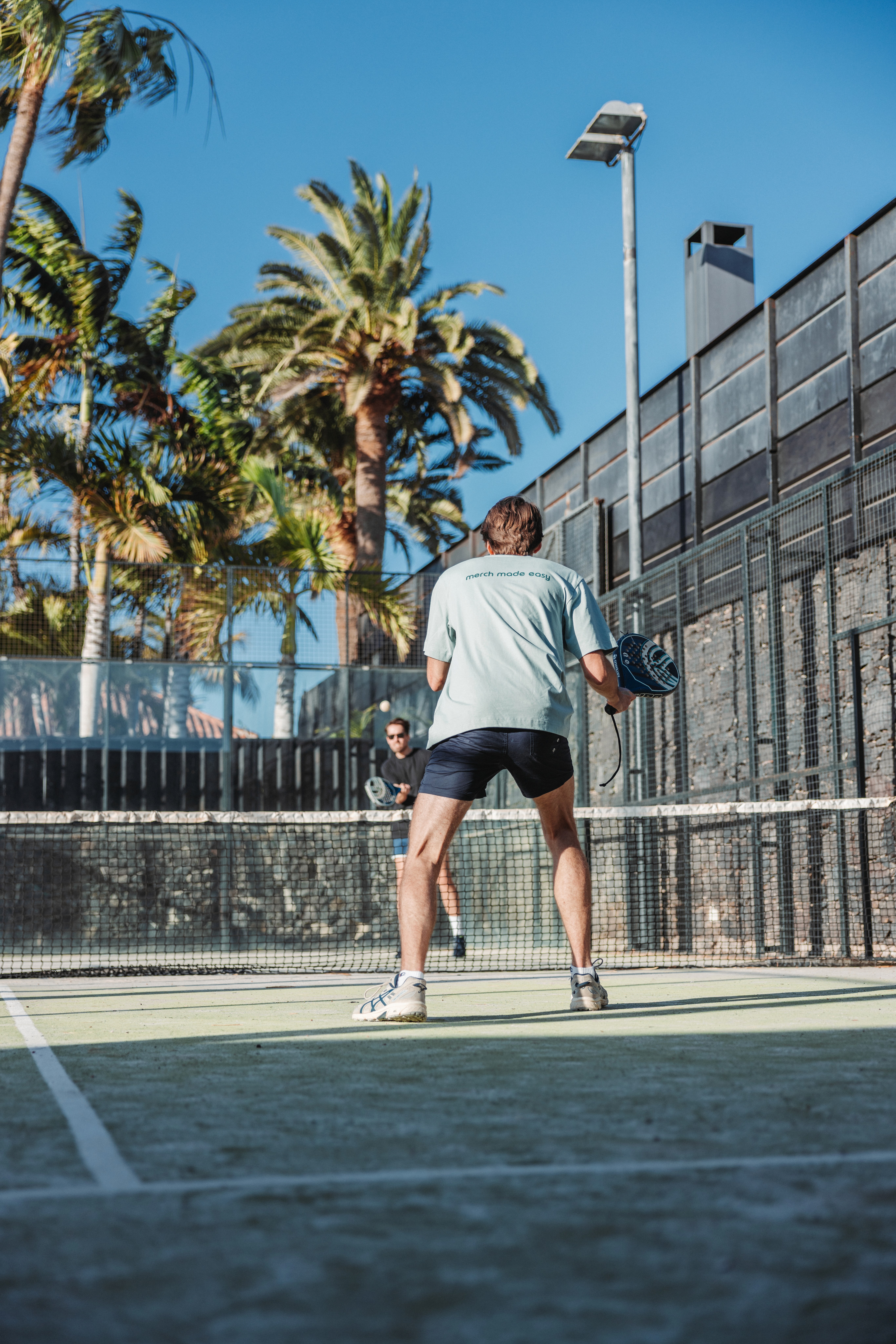 Deux personnes jouent au padel sur un court extérieur