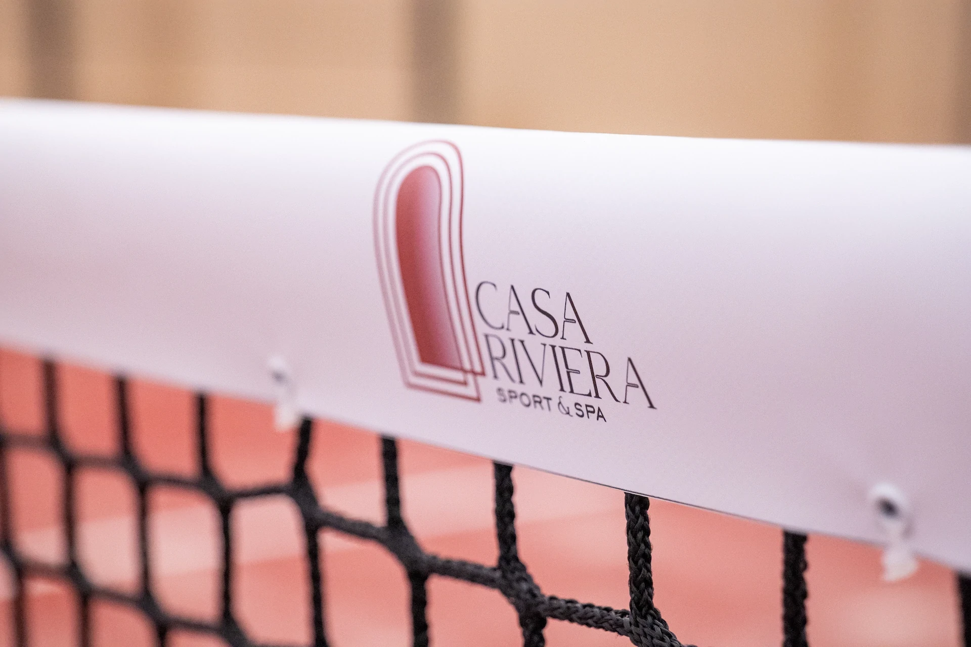 Logo Casa Riviera Sport & Spa sur filet de tennis. Vue rapprochée, sports et détente.