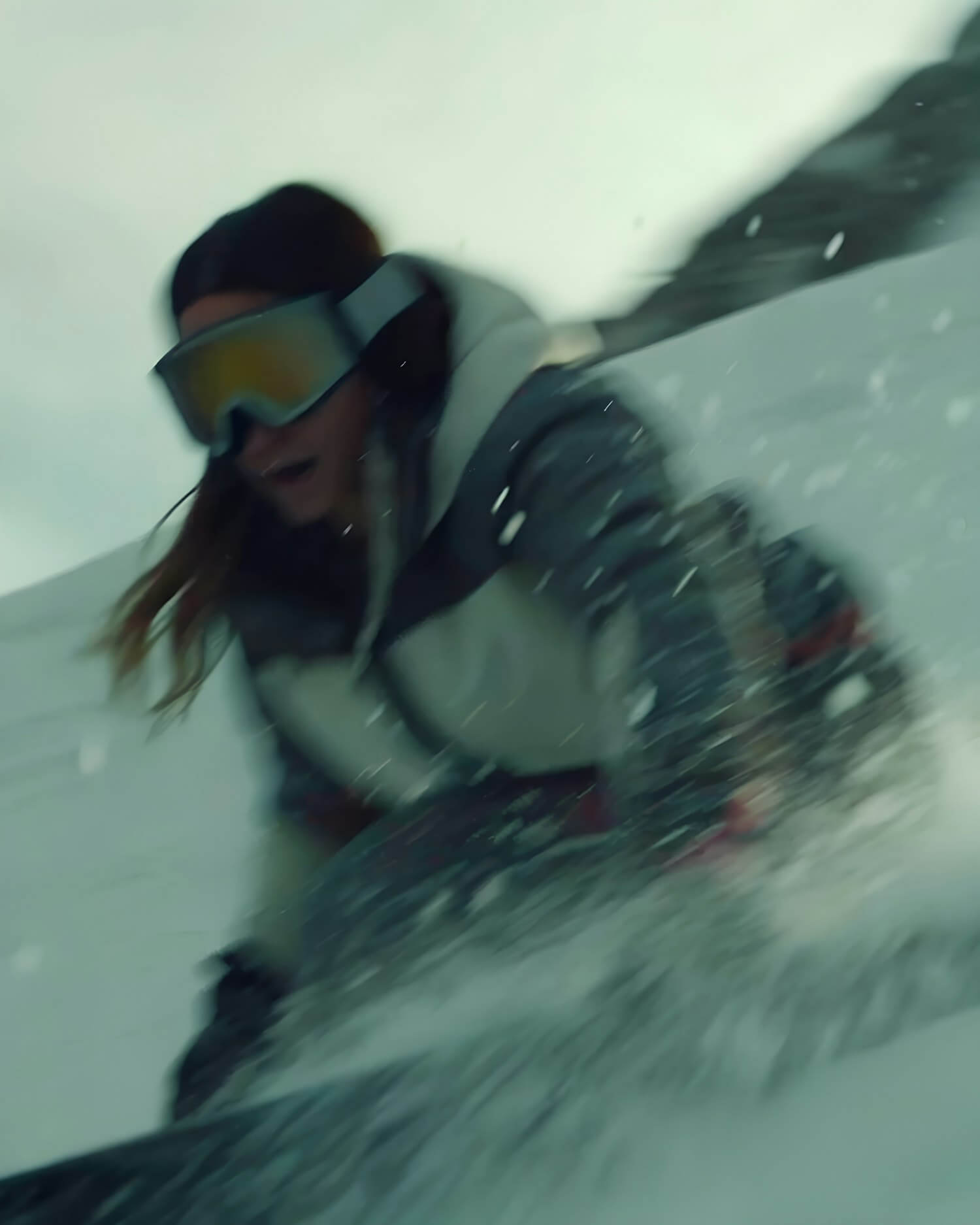 Snowboarder or skier sliding on snow with goggles and hooded jacket