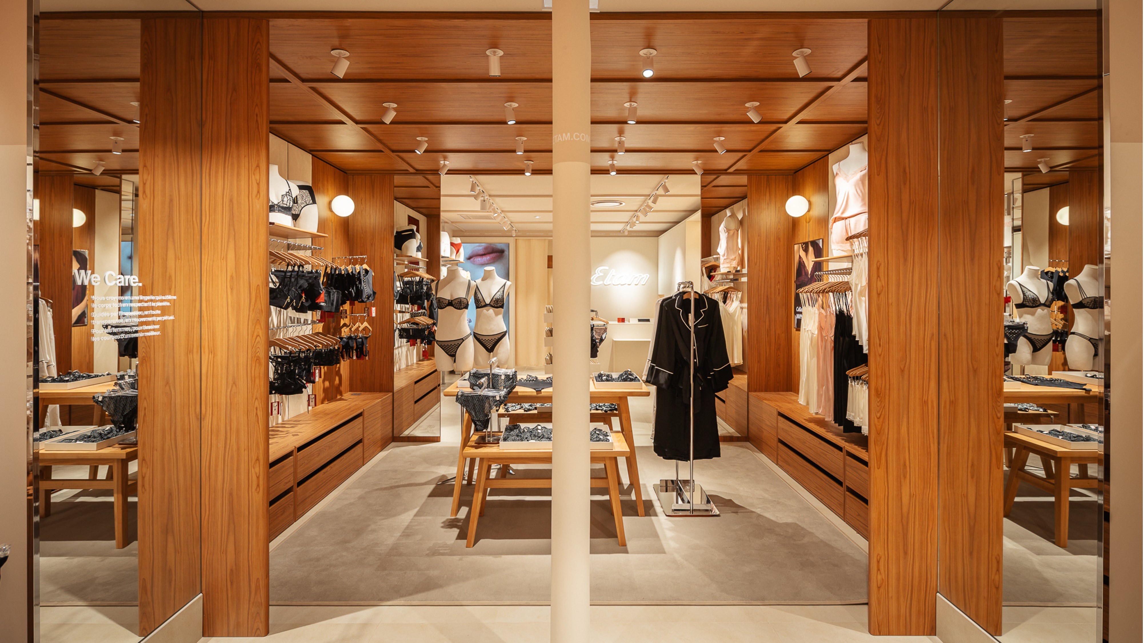 Intérieur de boutique ETAM avec lingerie exposée sur mannequins et présentoirs en bois, éclairage doux