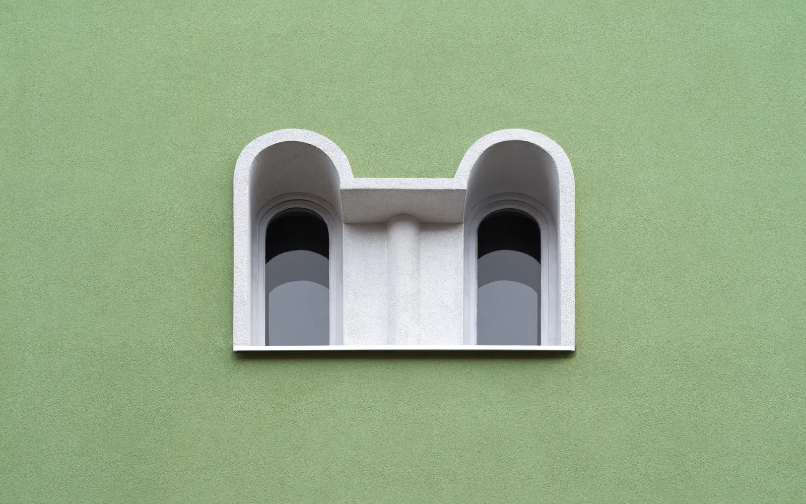 Two arched windows set into a plain green wall