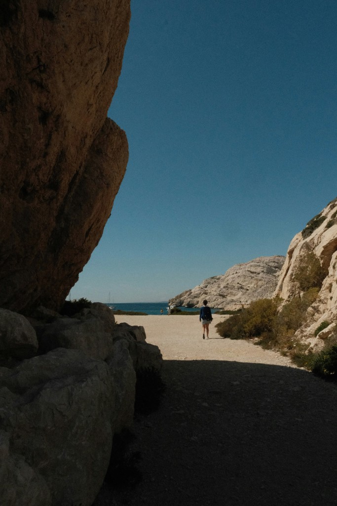 A person walking on a path between two large rocks