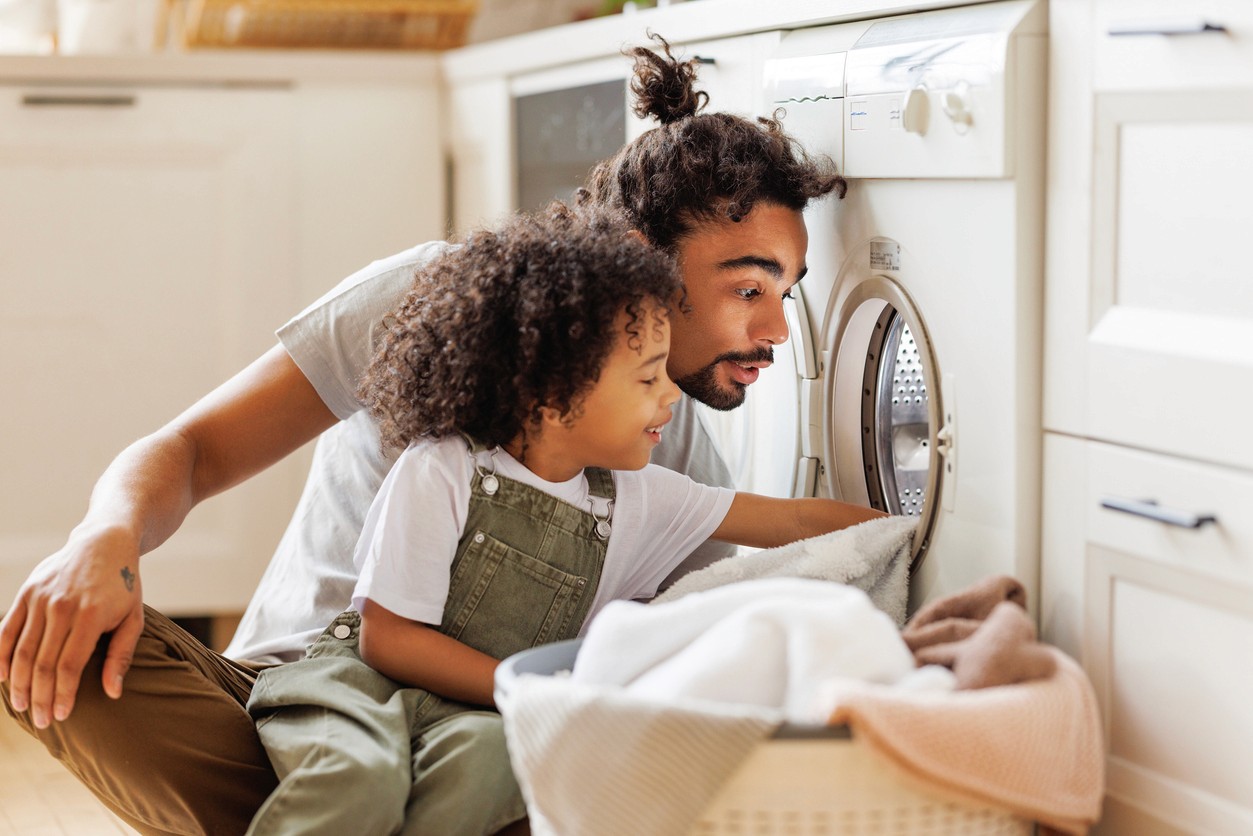 A father and son load towels into a dryer