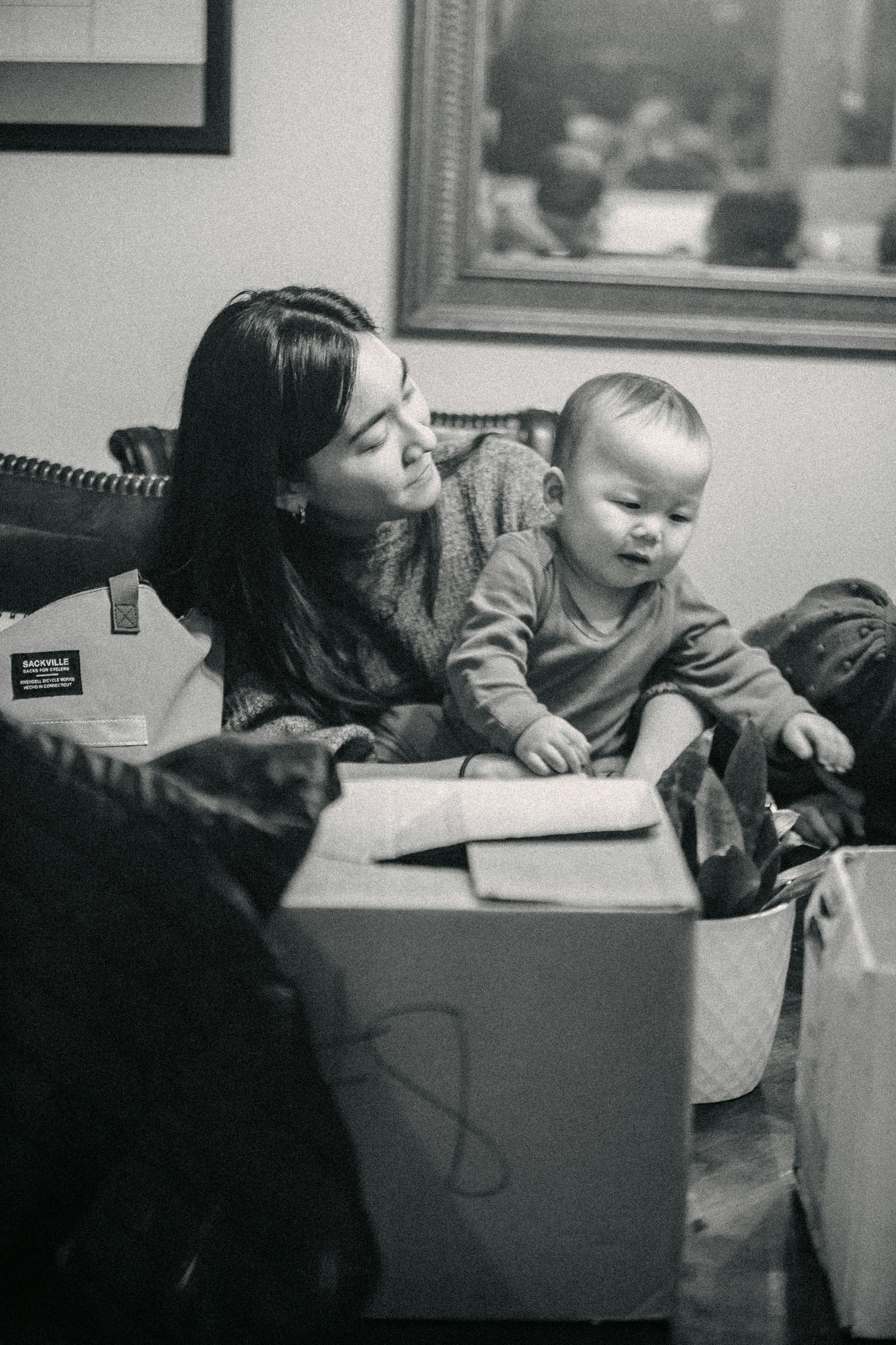 A mother and child sitting on the couch in front of a box with documents on top.