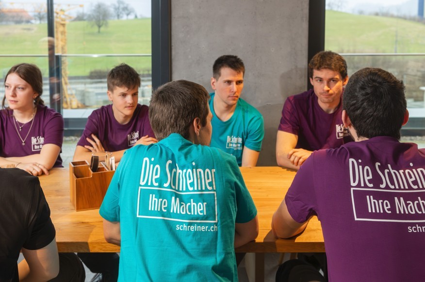 Foto mit Lernenden am Tisch zu sehen