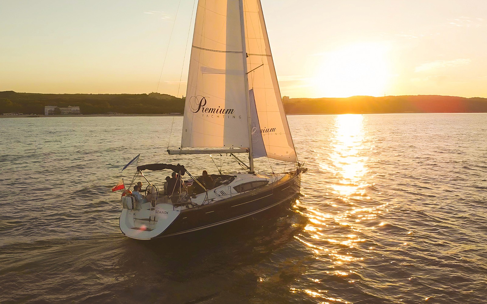 Sailboat on sunset cruise from Sopot Pier with sun setting over the water.
