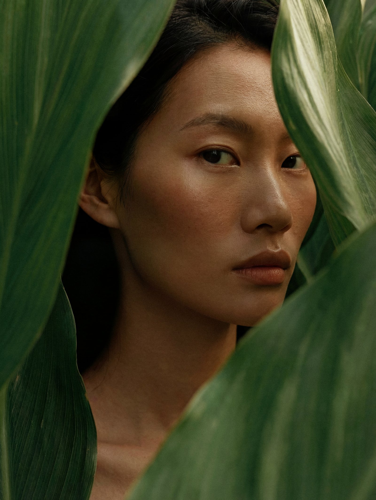 Woman framed by large green leaves
