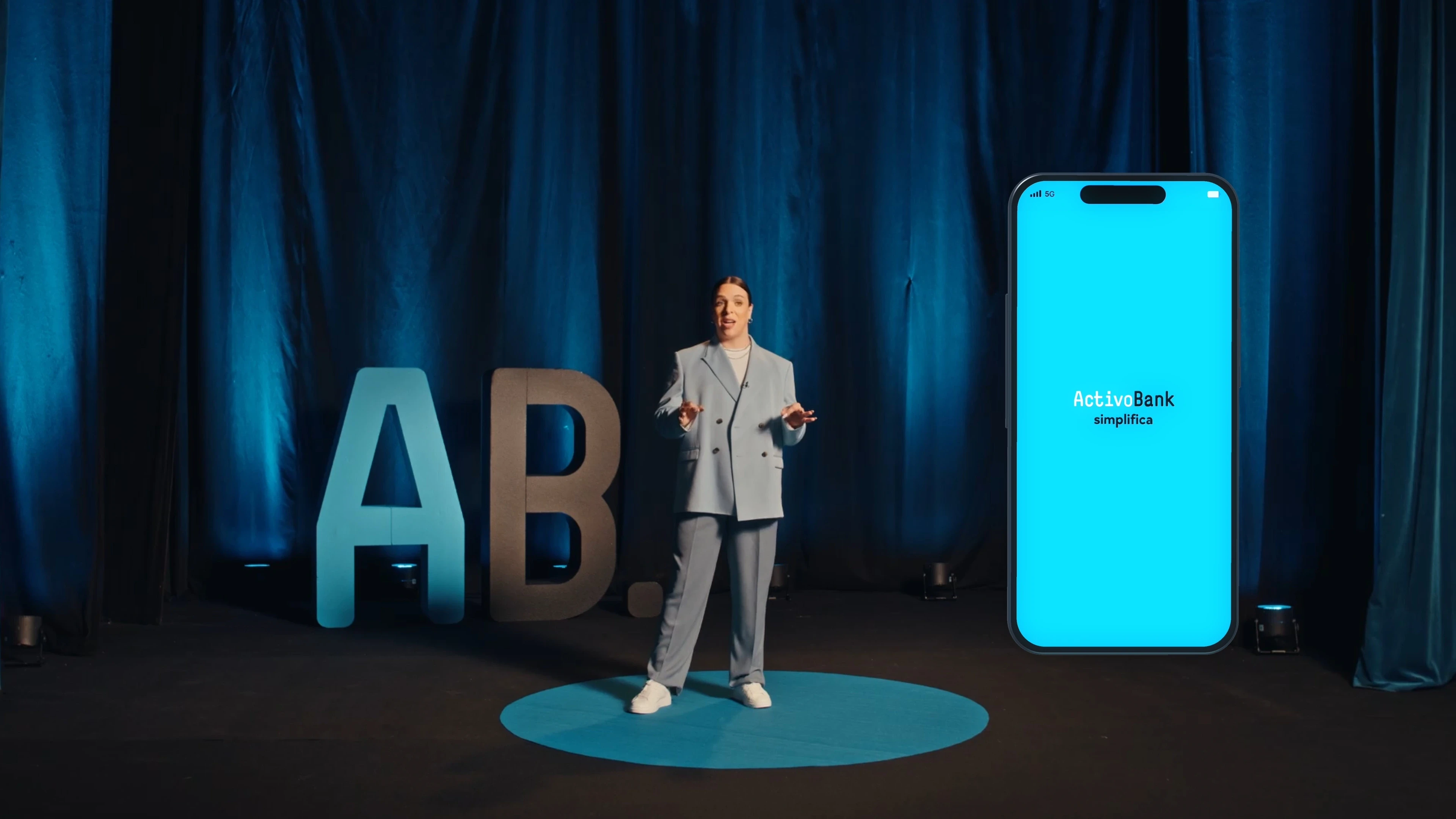 Kiko is Hot gives a TED-style talk next to a giant phone showing the ActivoBank app