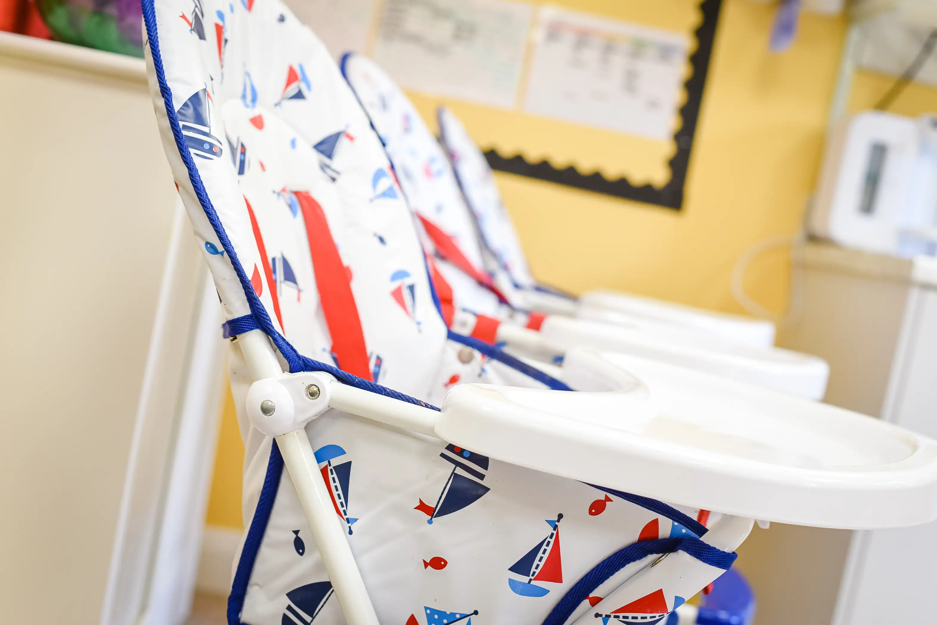 Row of high chairs with sail boat pattern for babies and toddlers