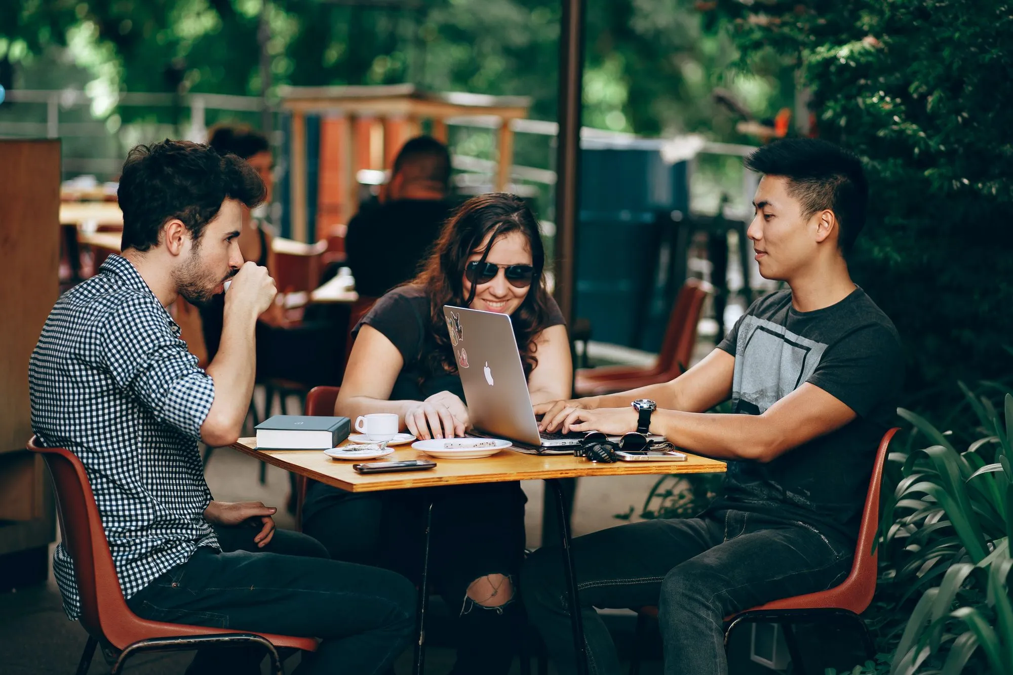 Three people with a laptop meeting at a cafe