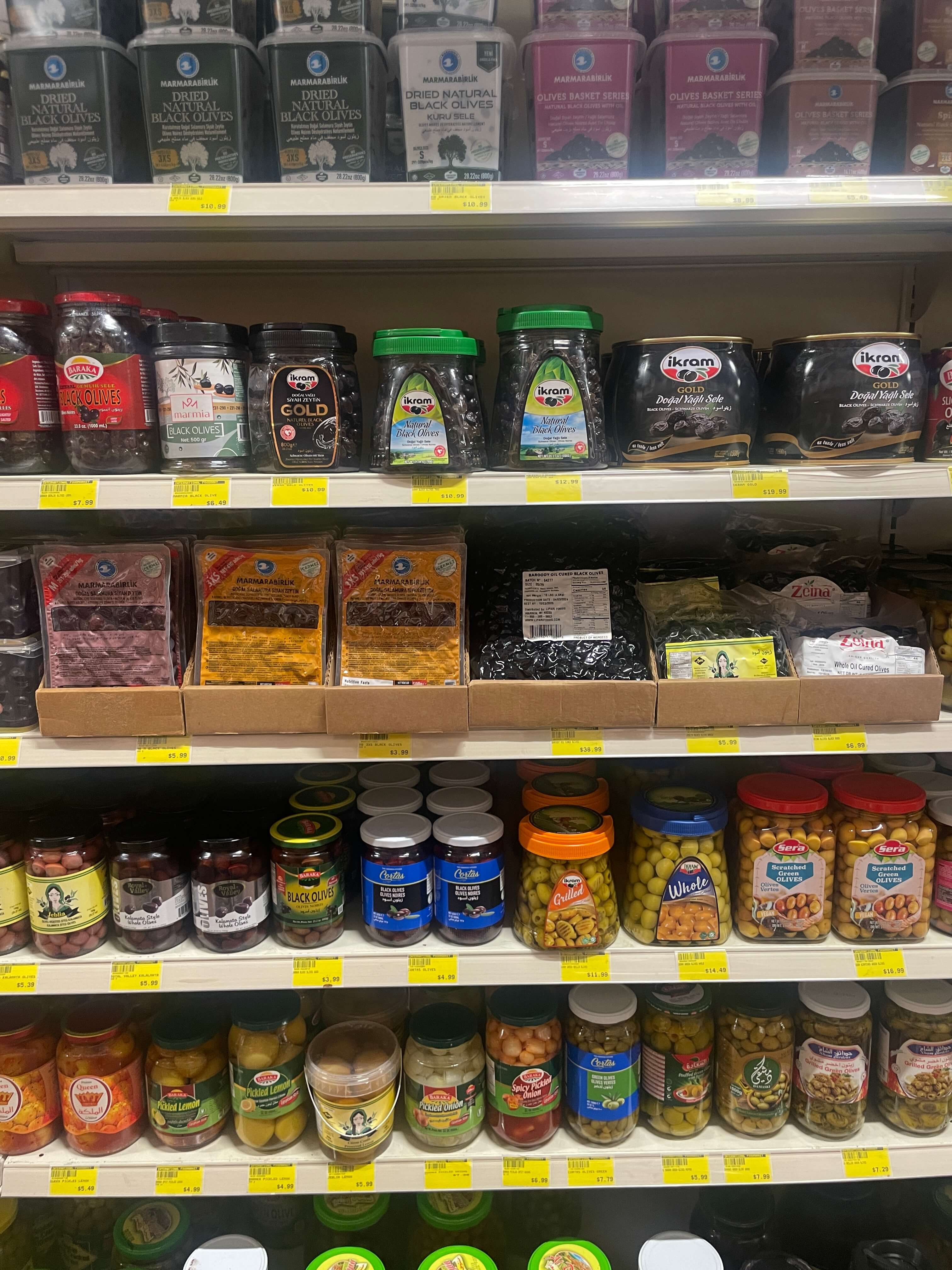 Shelf stocked with olive jars, pickled products, and canned goods at International Food Market Orlando.