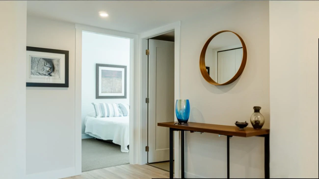 Elegant interior hallway with decorative mirror, wooden console table, and modern design elements in Burnaby custom home