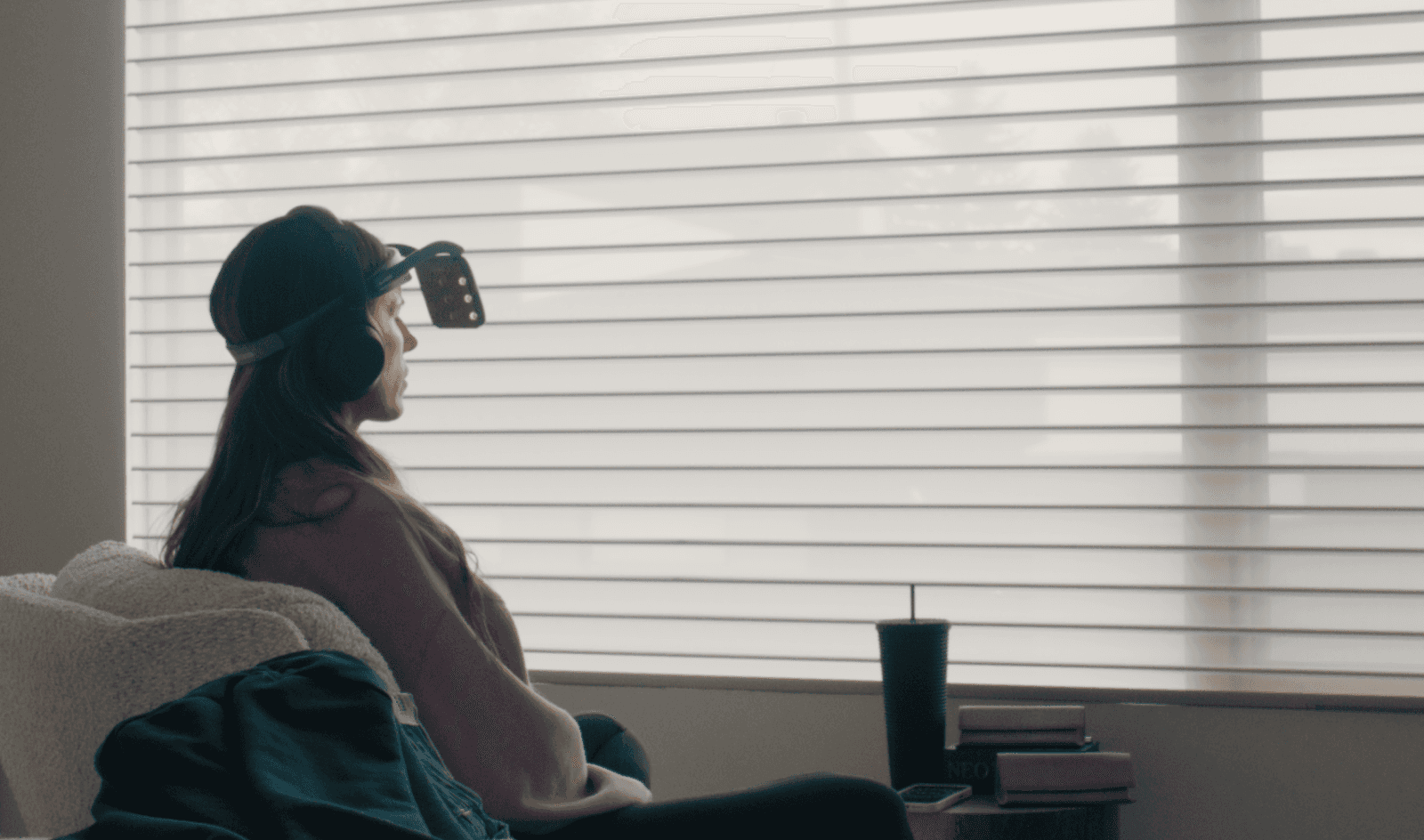 Woman sitting on a couch wearing headphones and a wearable tech therapy device
