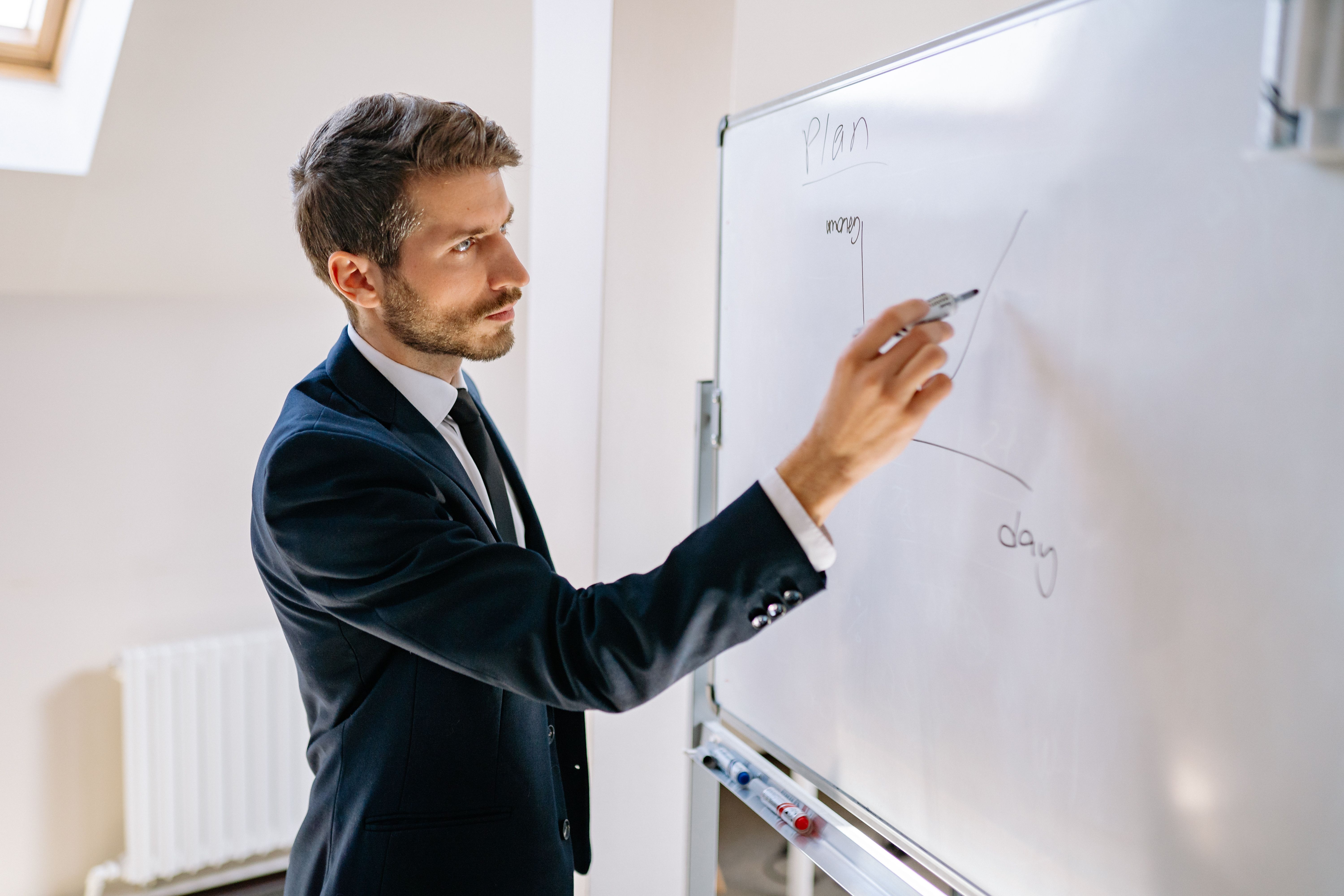 executive-in-suit-writing-on-whiteboard,-explaining-business-graph. - yan-krukau (pexels)