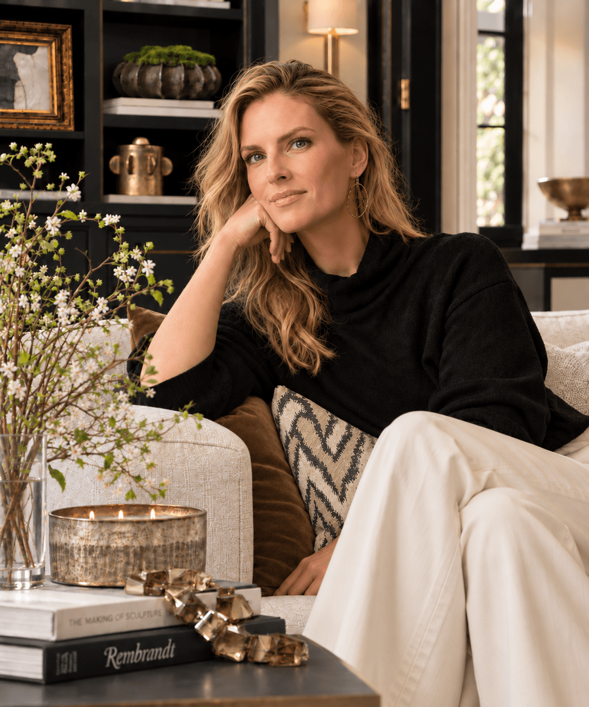 Carrie Lewis seated amid brass, velvet, and botanicals