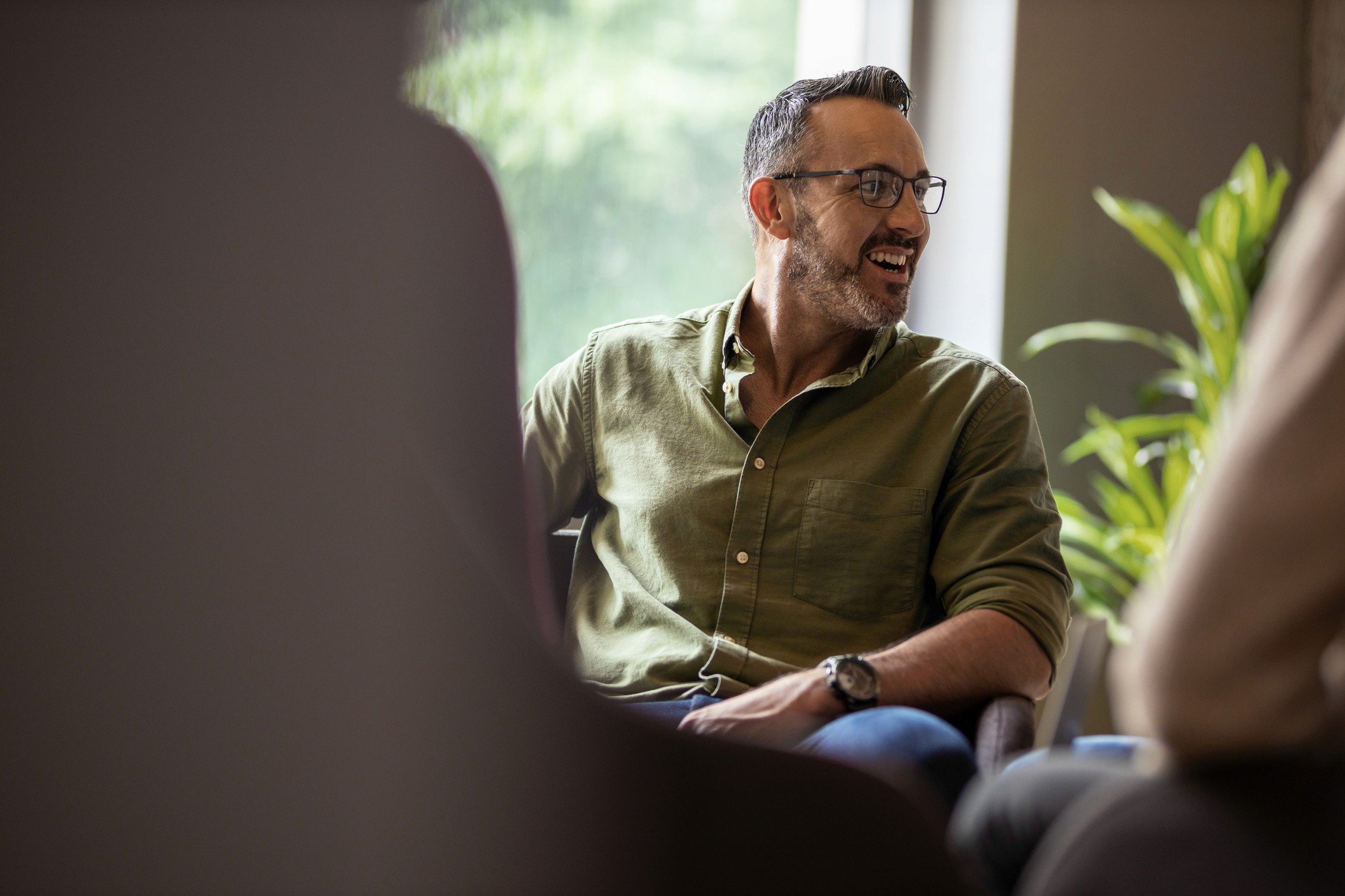 Man in glasses and olive shirt talking.