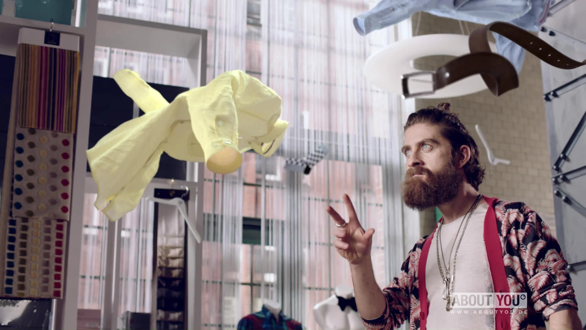 A man looking discerningly at clothes floating through the air.