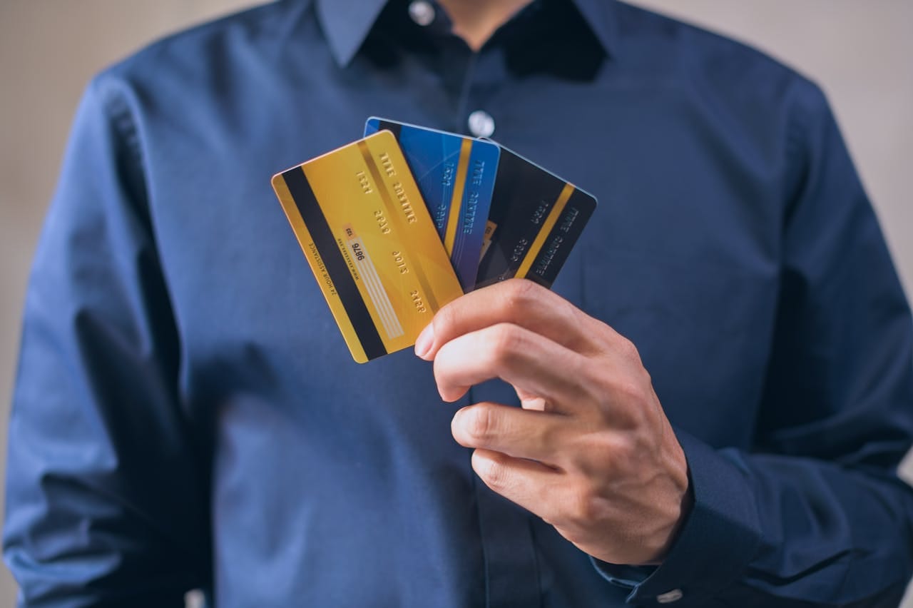 Close-up shot of a man holding three separate credit cards.