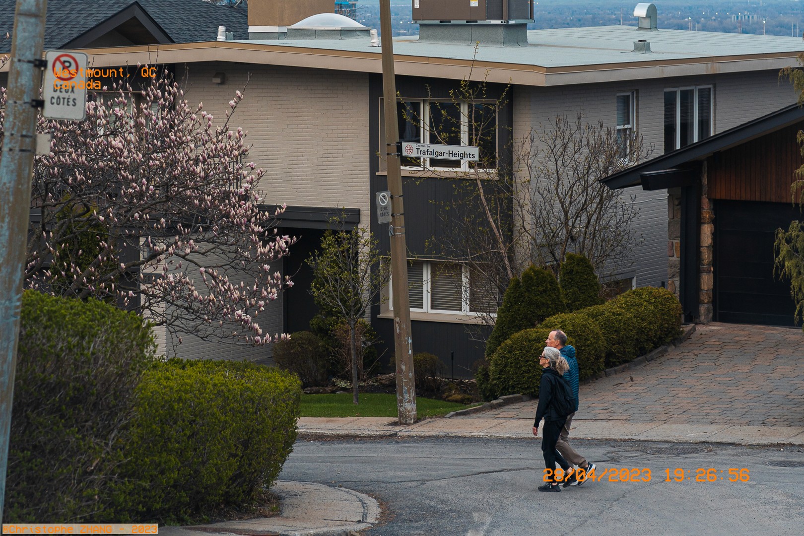 Scène tranquille à Westmount avec un couple se promenant devant une maison moderne.