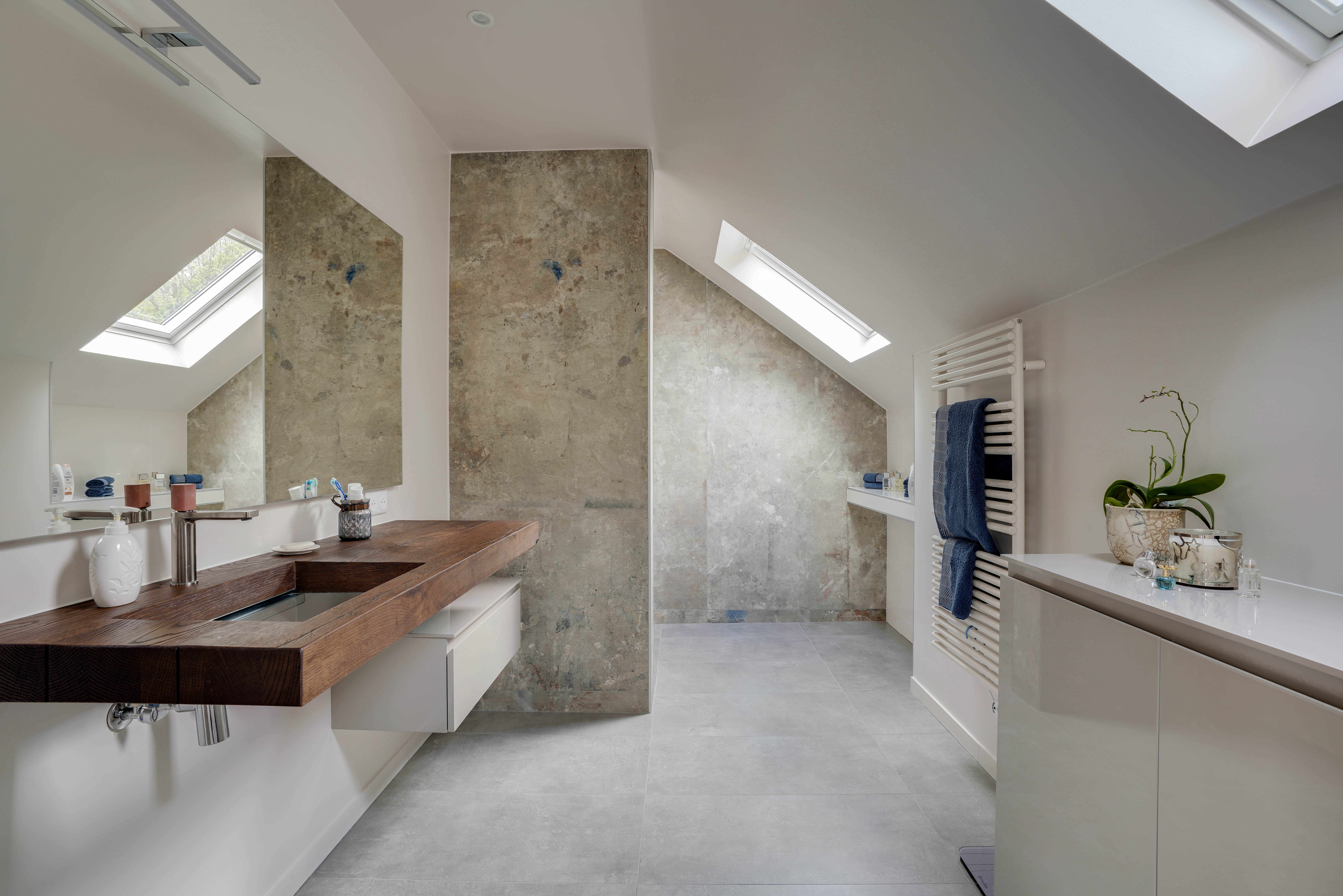 Rénovation salle de bains mansardée 77 avec plafonds inclinés, puits lumière, comptoir lavabo bois et douche italienne, architecte d'intérieur.