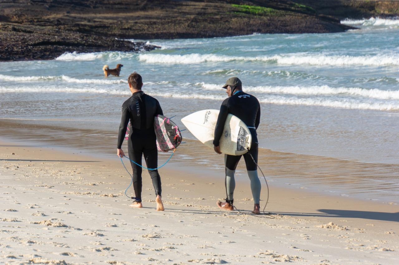 Dois homens andando com pranchas de surfe