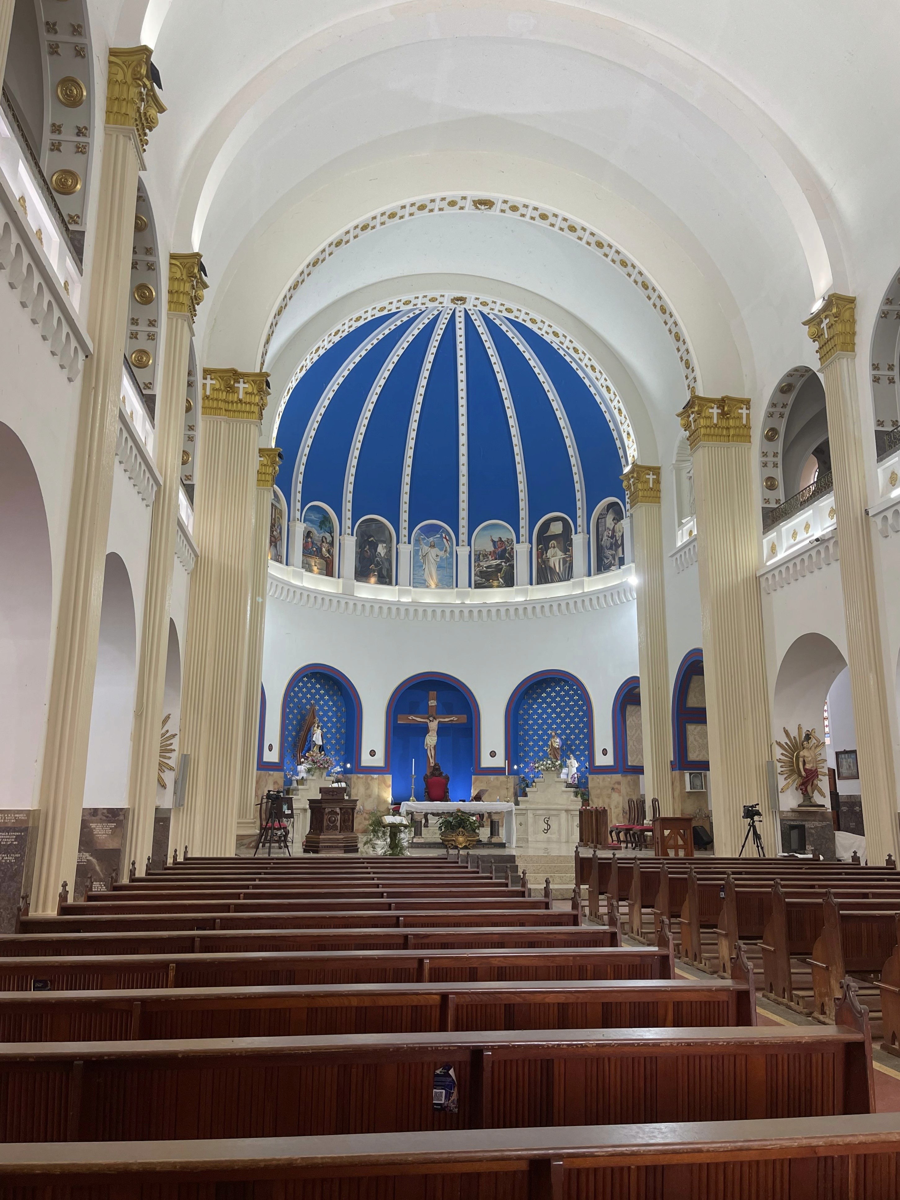A couple stands hand-in-hand in front of a rustic stone building.
