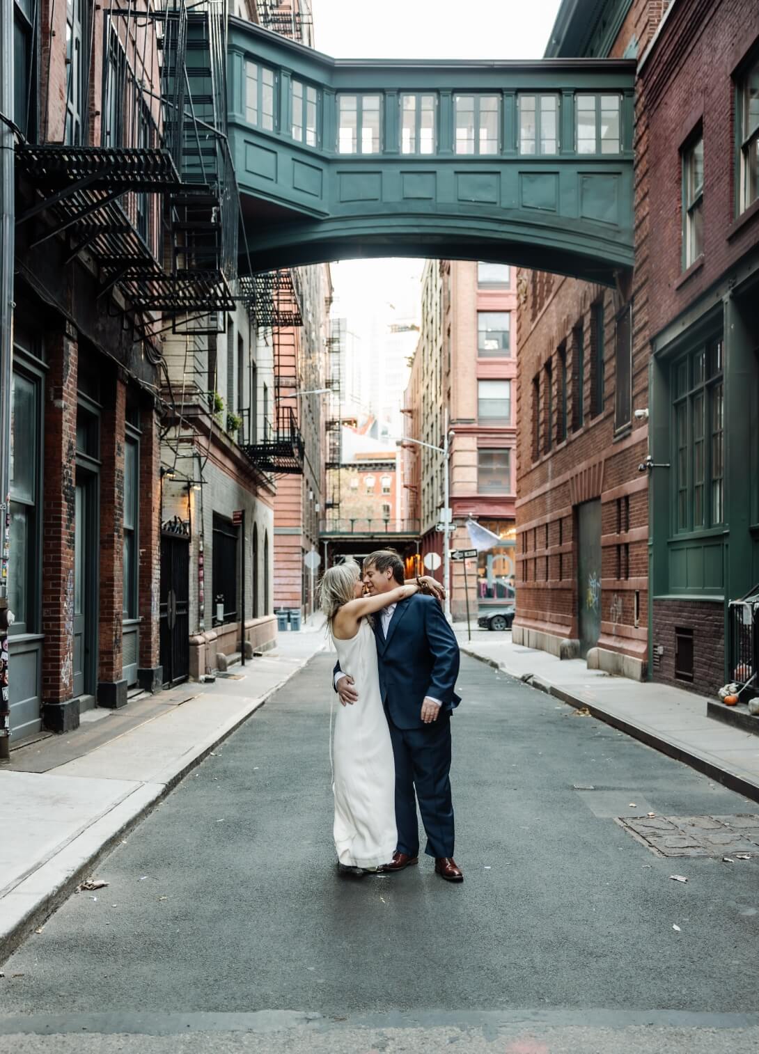Couple renewing their vows beneath the iconic Staple Street Bridge in Tribeca, NYC, wrapped in each other's arms and lost in each other's eyes — romantic couples photography by Lizz Spano Photography, New York City photographer.