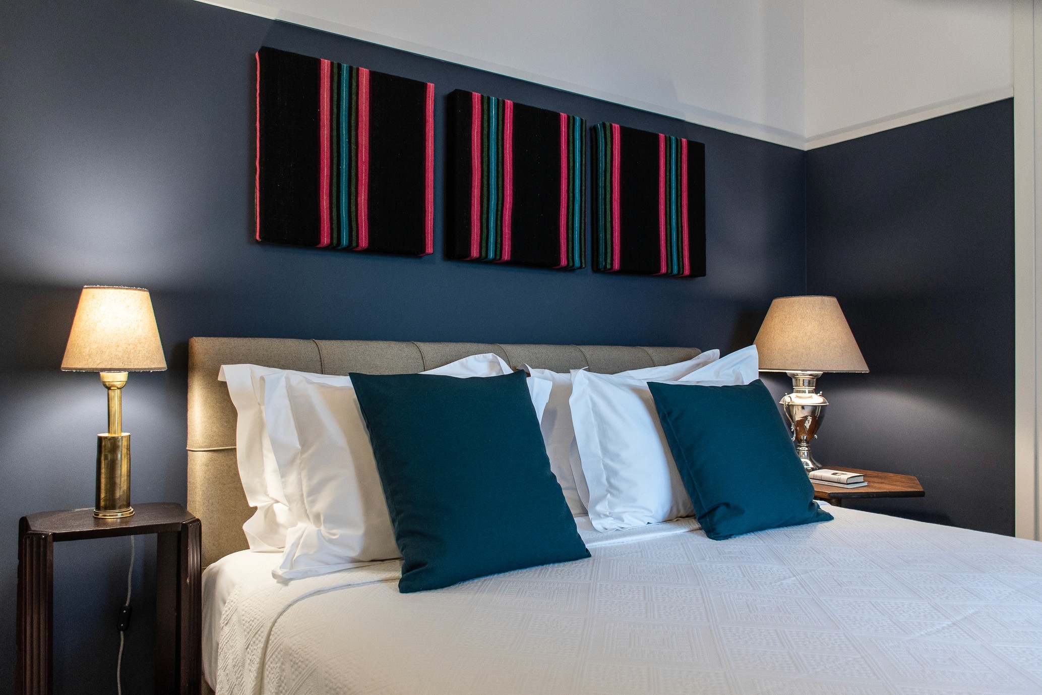 A bedroom with blue walls and a striped artwork with white linen - House 2 Eros Keros