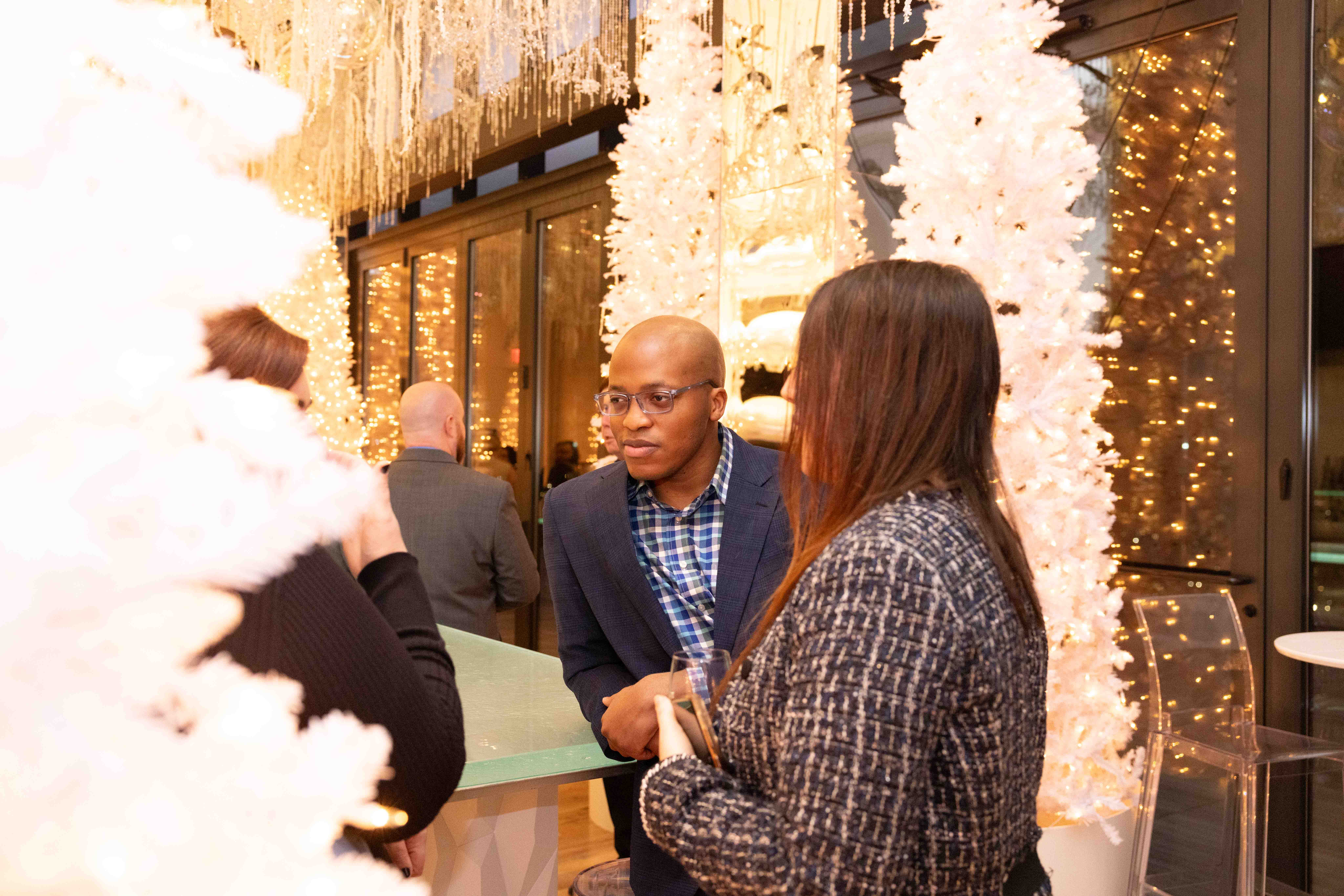 person discussing while standing in front of a large screen in front of people inside dim-lighted room