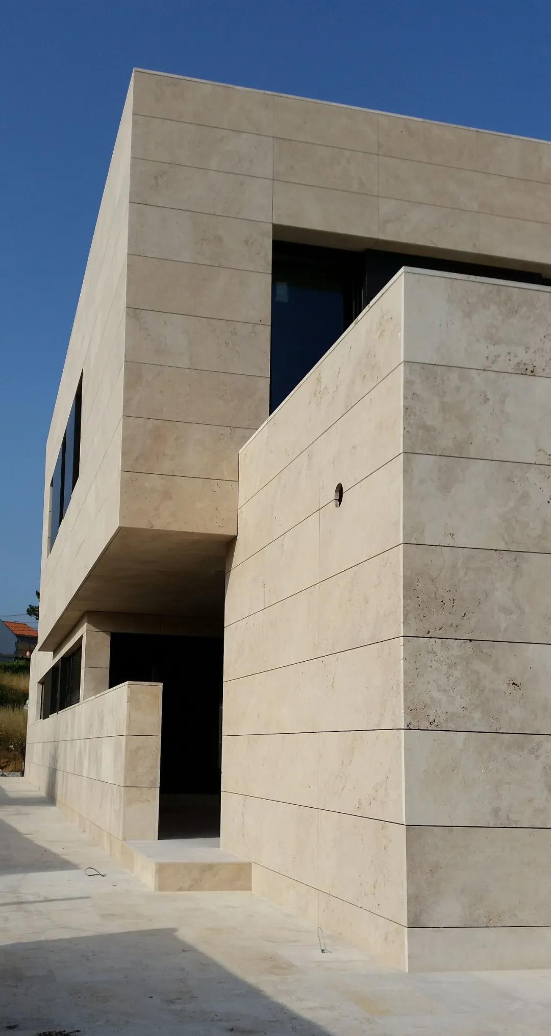  A modern building exterior showcasing beige travertine stone cladding, creating a minimalist and sleek architectural appearance. 