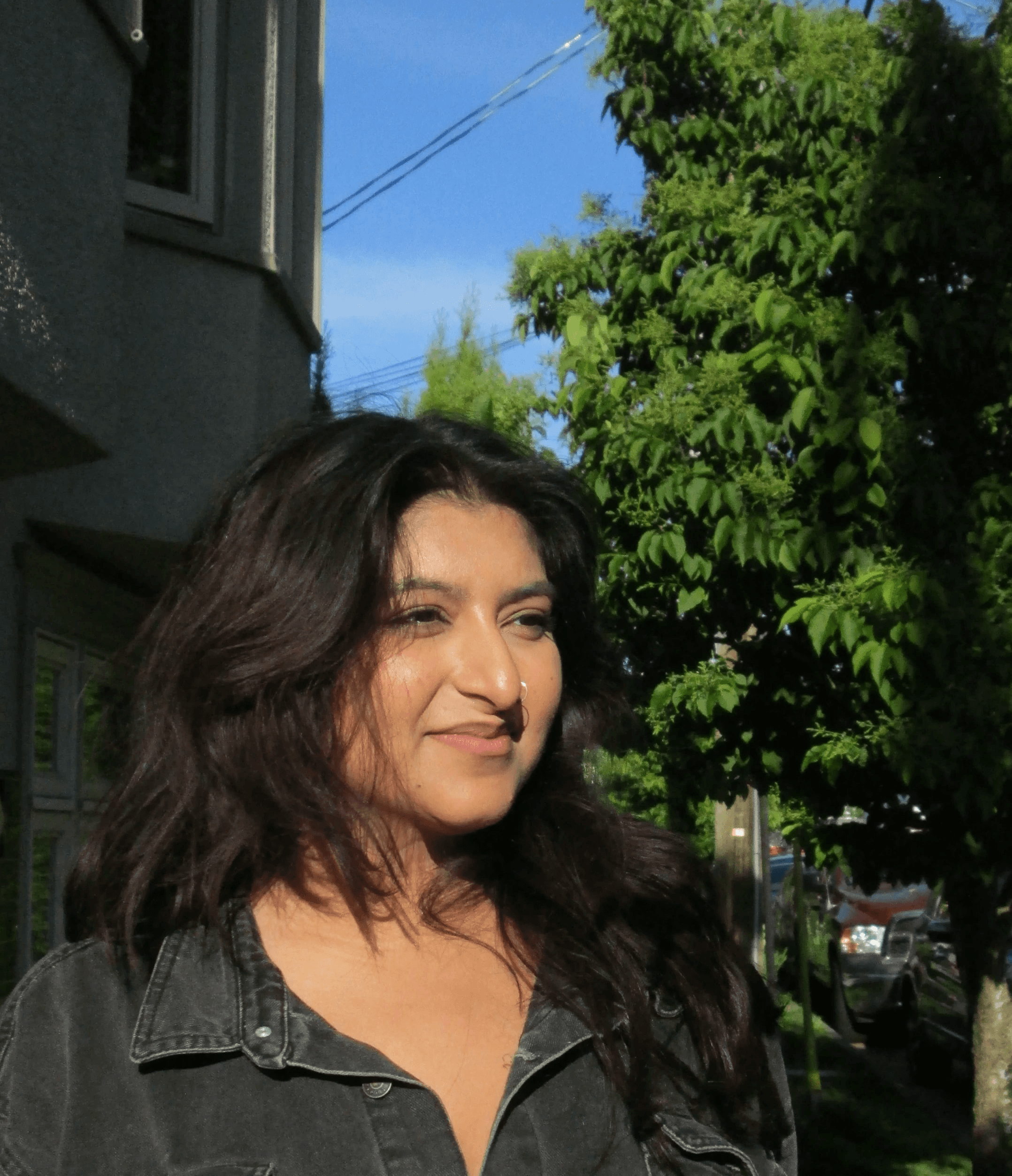 A thoughtful young person with dark hair gazes to the side, captured in soft black and white lighting.