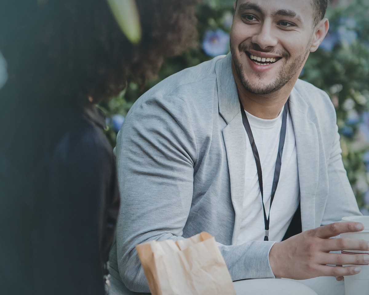 An Accountable peer coach smiling in conversation over coffee