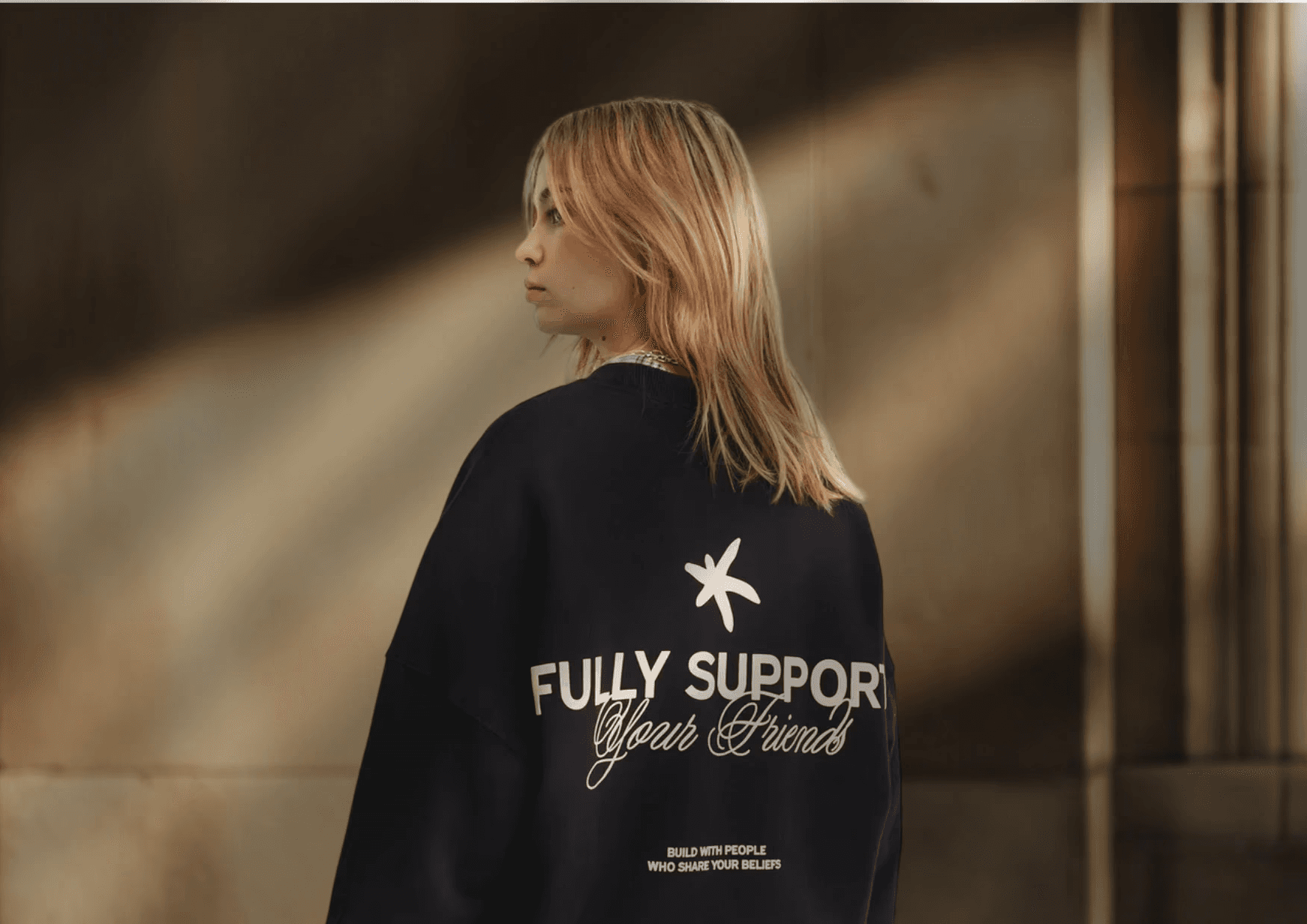 woman in gray hoodie holding white ceramic mug