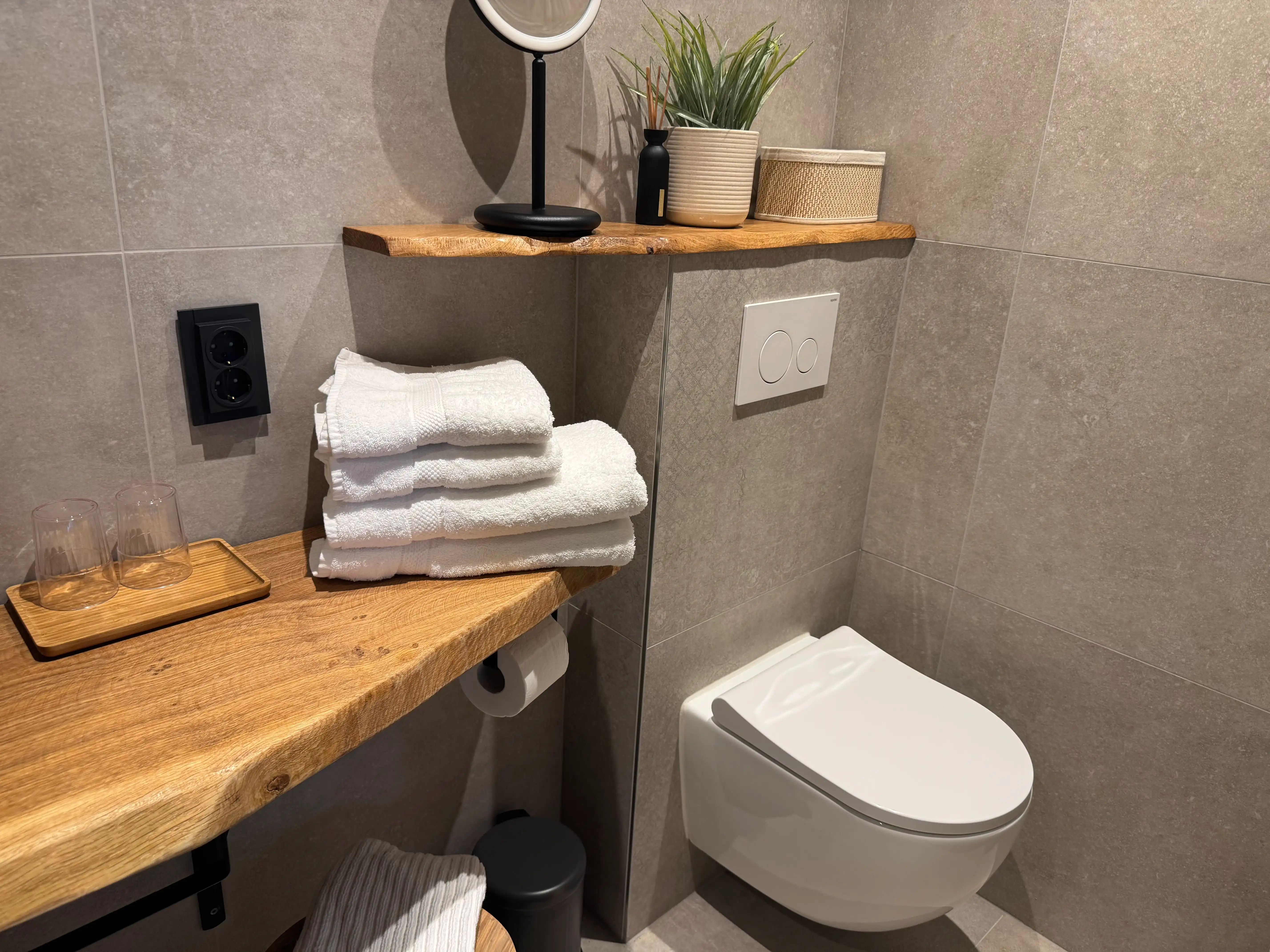 Modern toilet met houten wandplanken en witte handdoeken inbegrepen.