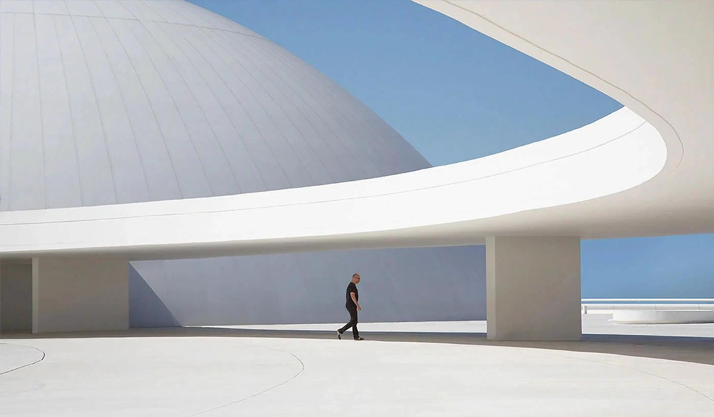 Person walking through a curved white architectural hall