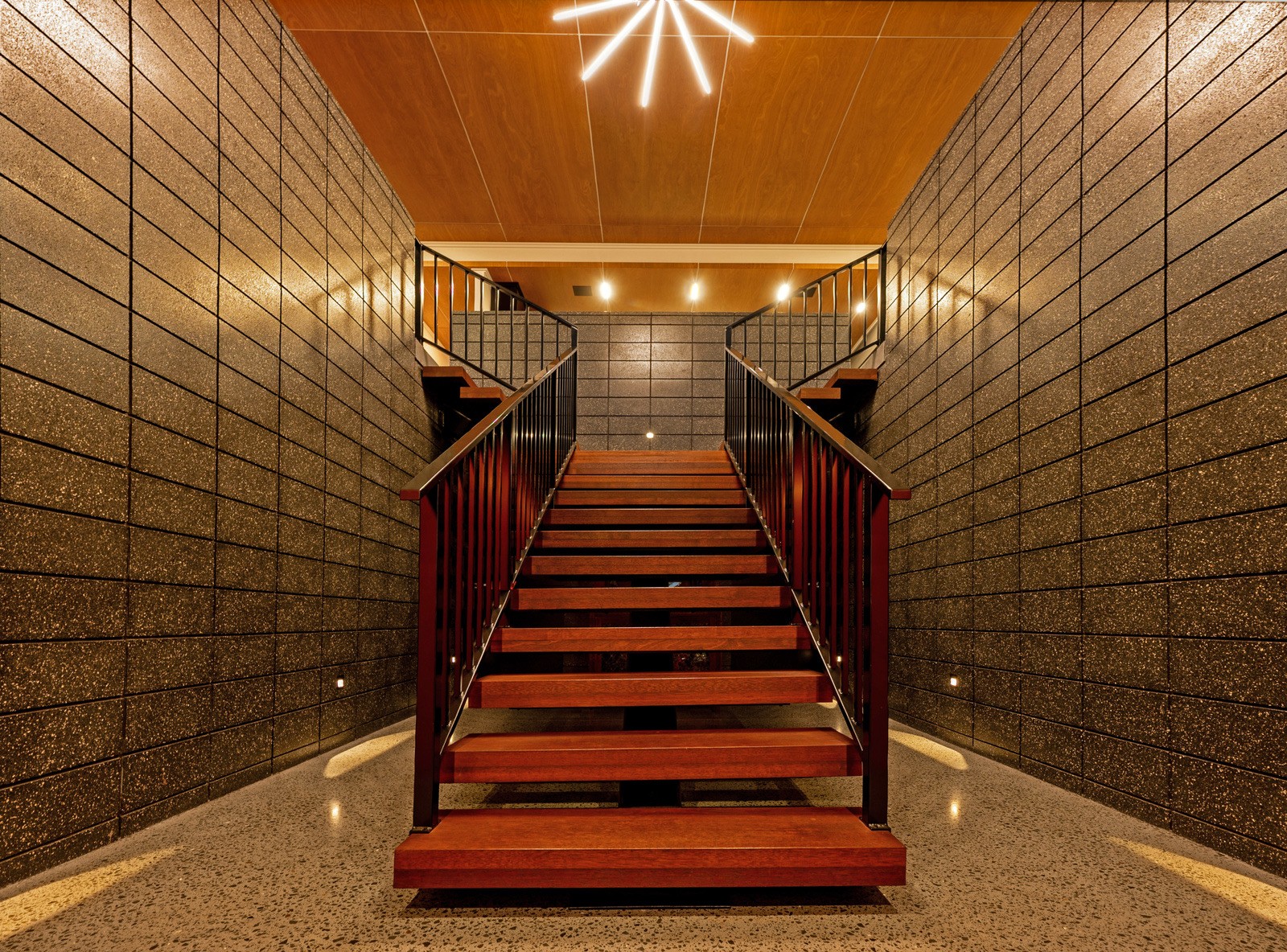 Timber staircase with black balustrade and textured block walls at the Florey Heights home