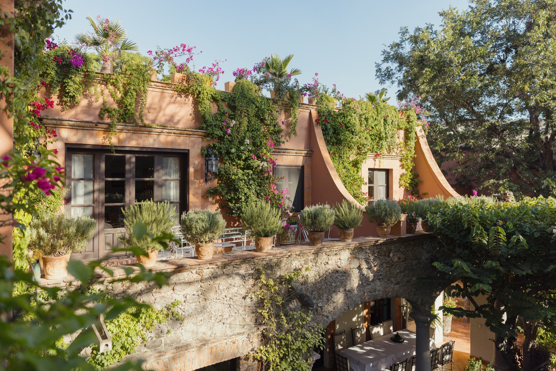 La Residencia sun-lit terrace with wrought iron seating and potted herbs