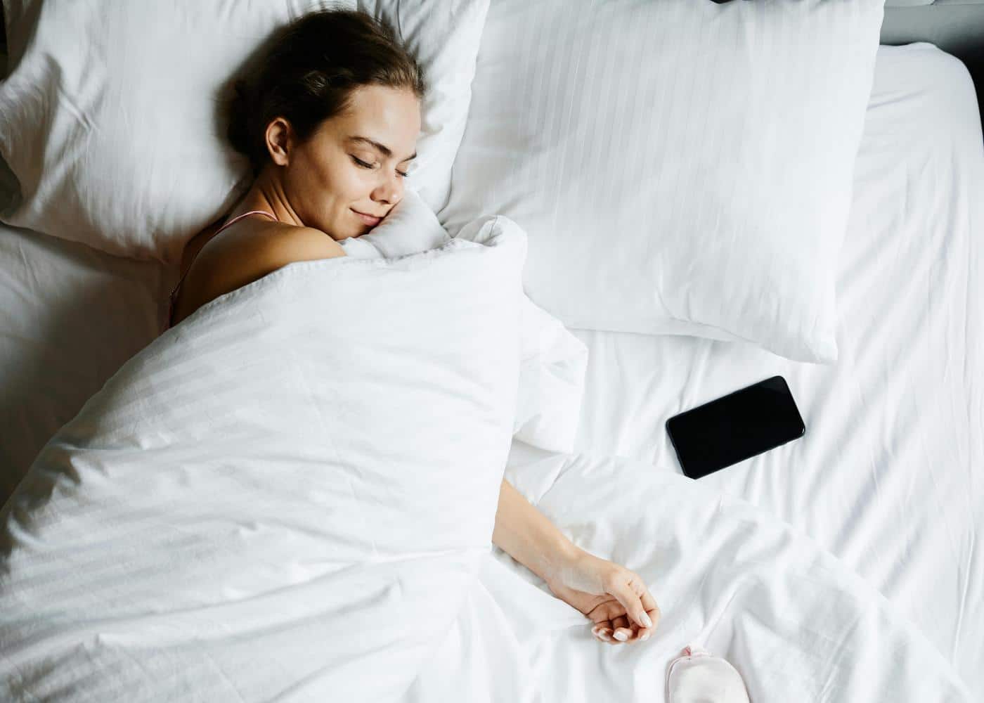 Woman peacefully sleeping on a bed with an iPhone by her side